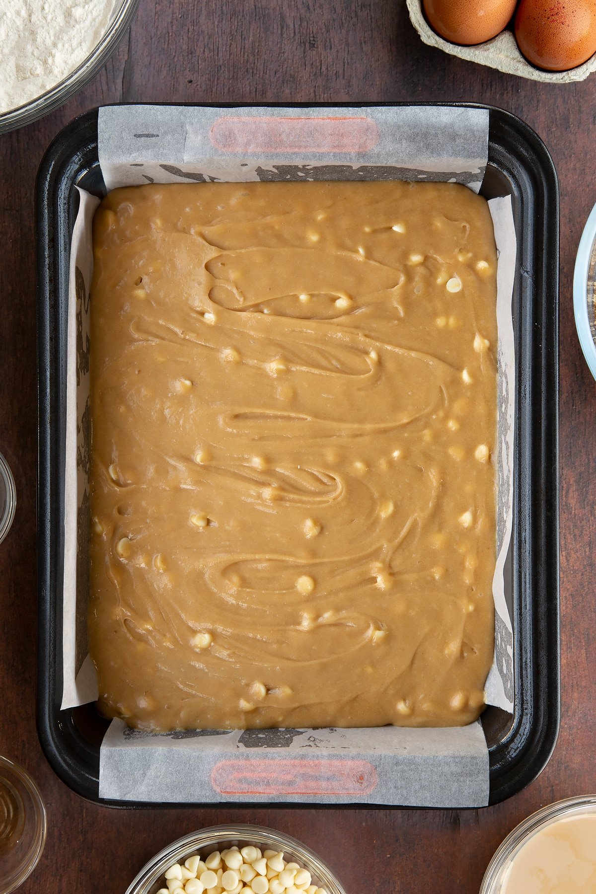 Baileys blondie batter with white chocolate chips in a lined tin.