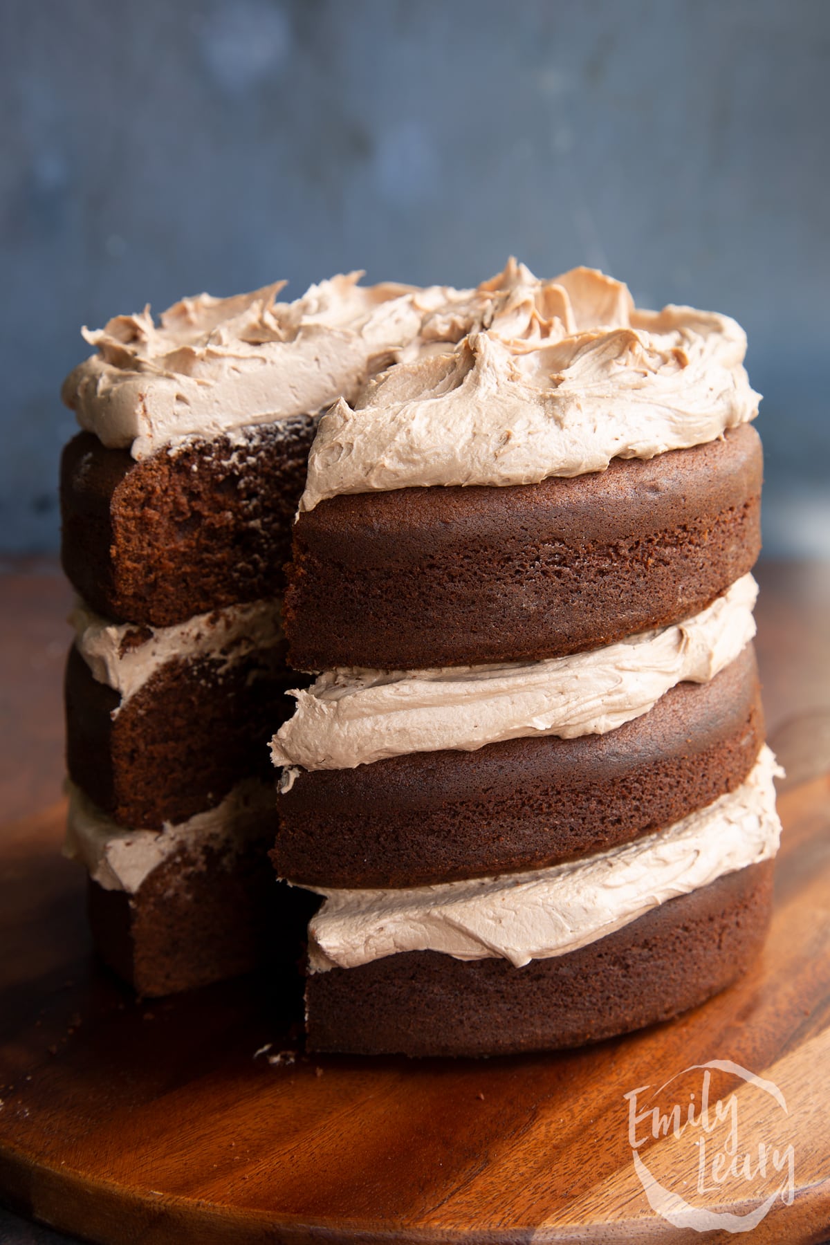 Three tier chocolate Baileys cake, sandwiched and topped with Baileys buttercream frosting. A slice has been cut away.