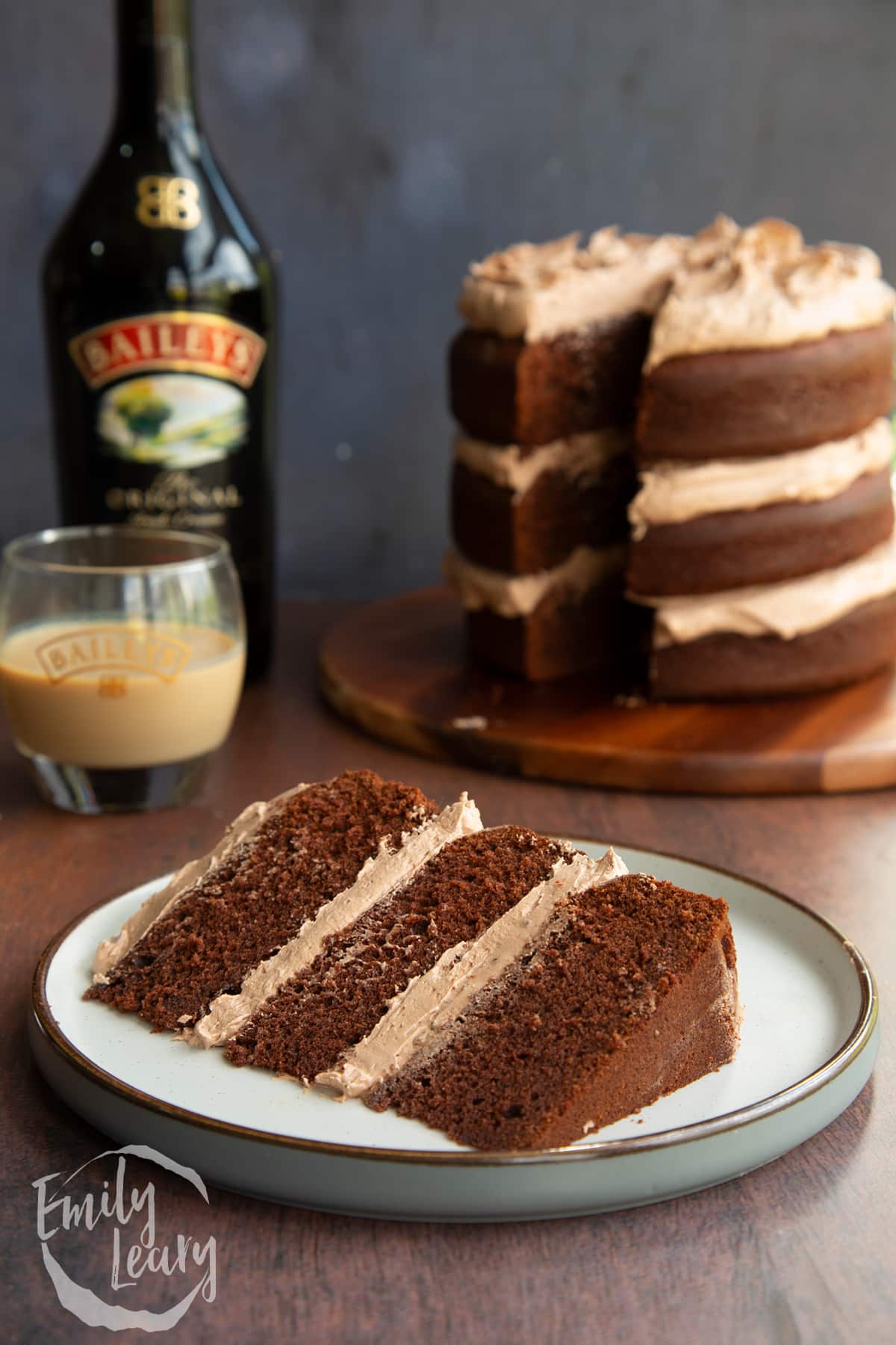 Slice of chocolate Baileys cake with Baileys buttercream frosting on a white plate.