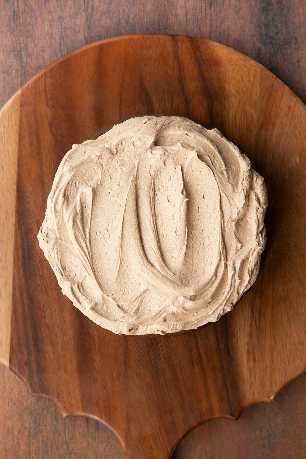 A layer of Baileys chocolate cake, topped with Baileys icing on a wooden board.