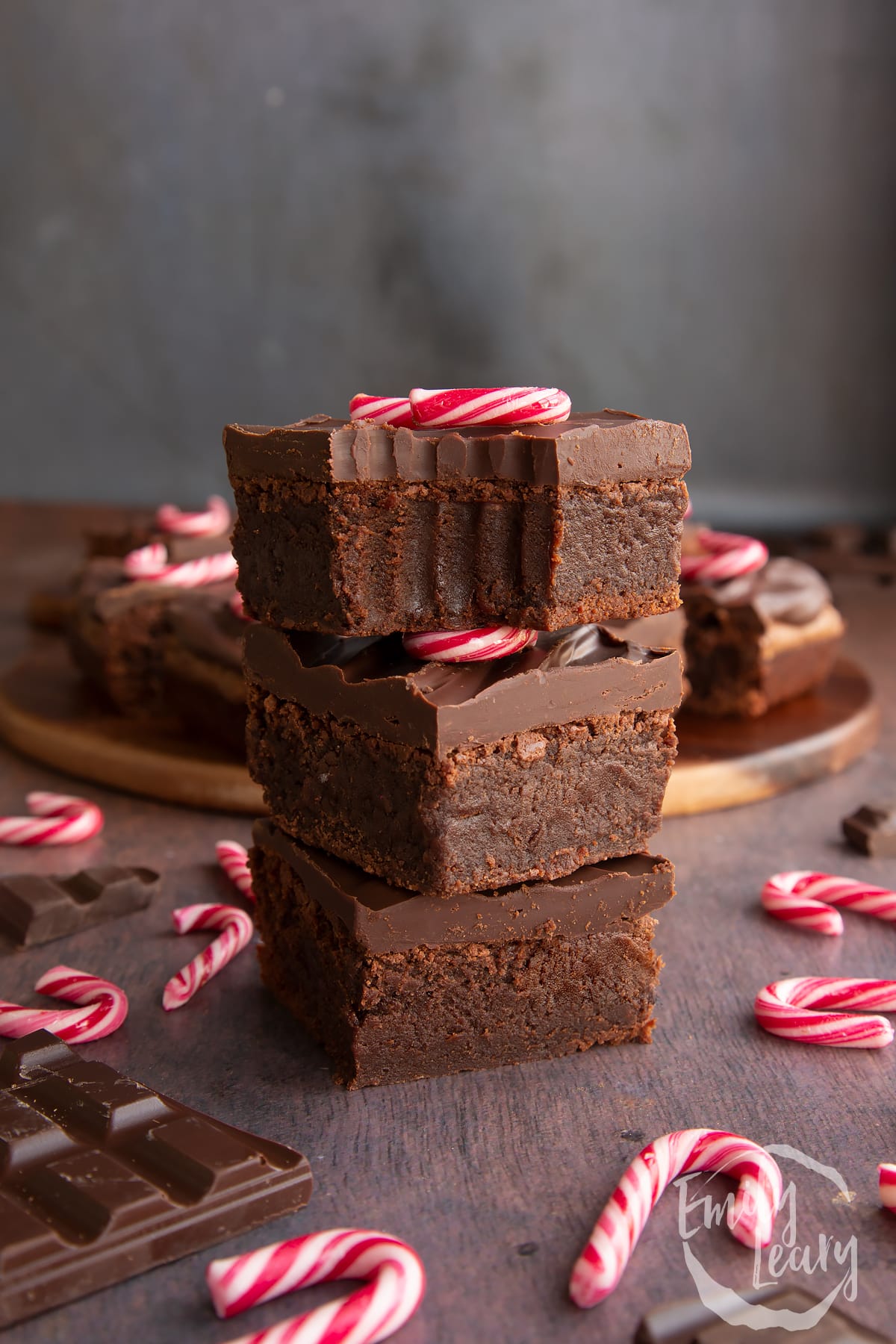 Three candy cane brownies stacked with more in the background. One has a bite out of it.
