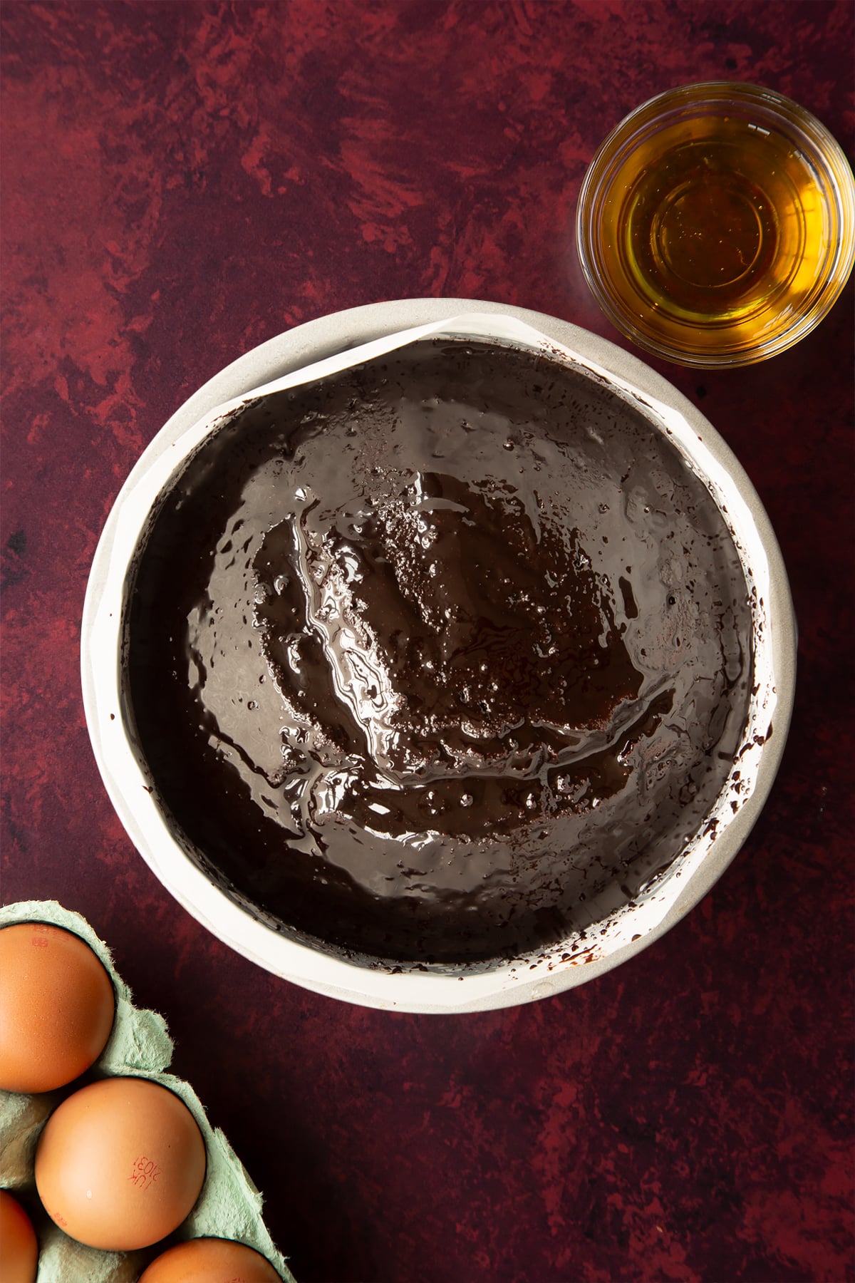 Chocolate drizzle cake, drizzled with syrup in a lined tin.