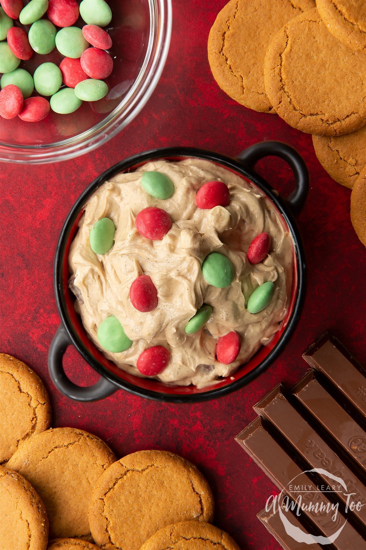 Christmas cookie dip in a black pot, surrounded by ingredients. Shown from above.