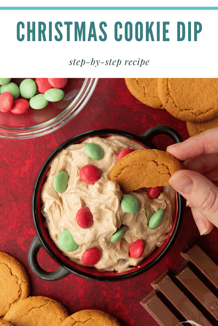 Christmas cookie dip in a black pot. A hand dips a piece of gingernut cookie into the dip. Caption reads: Christmas cookie dip. Step-by-step recipe.