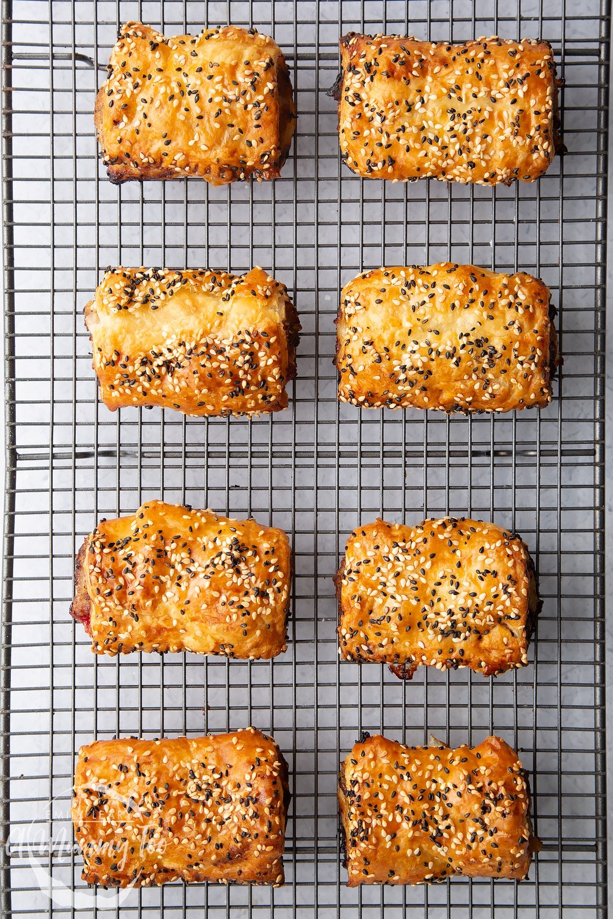 Festive sausage rolls on a wire cooling rack.