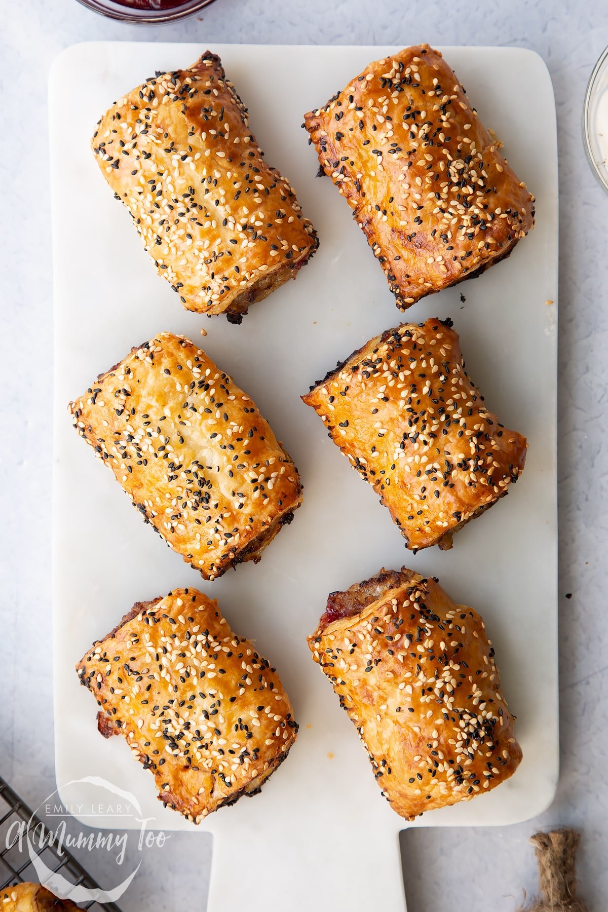 Festive sausage rolls on a white marble board.