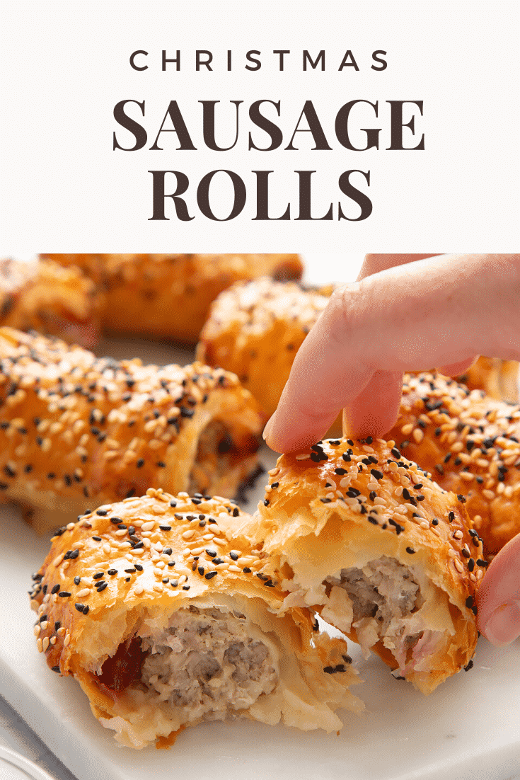 A festive sausage roll broken open on a white marble board. A hand reaches for it. Caption reads: Christmas sausage rolls