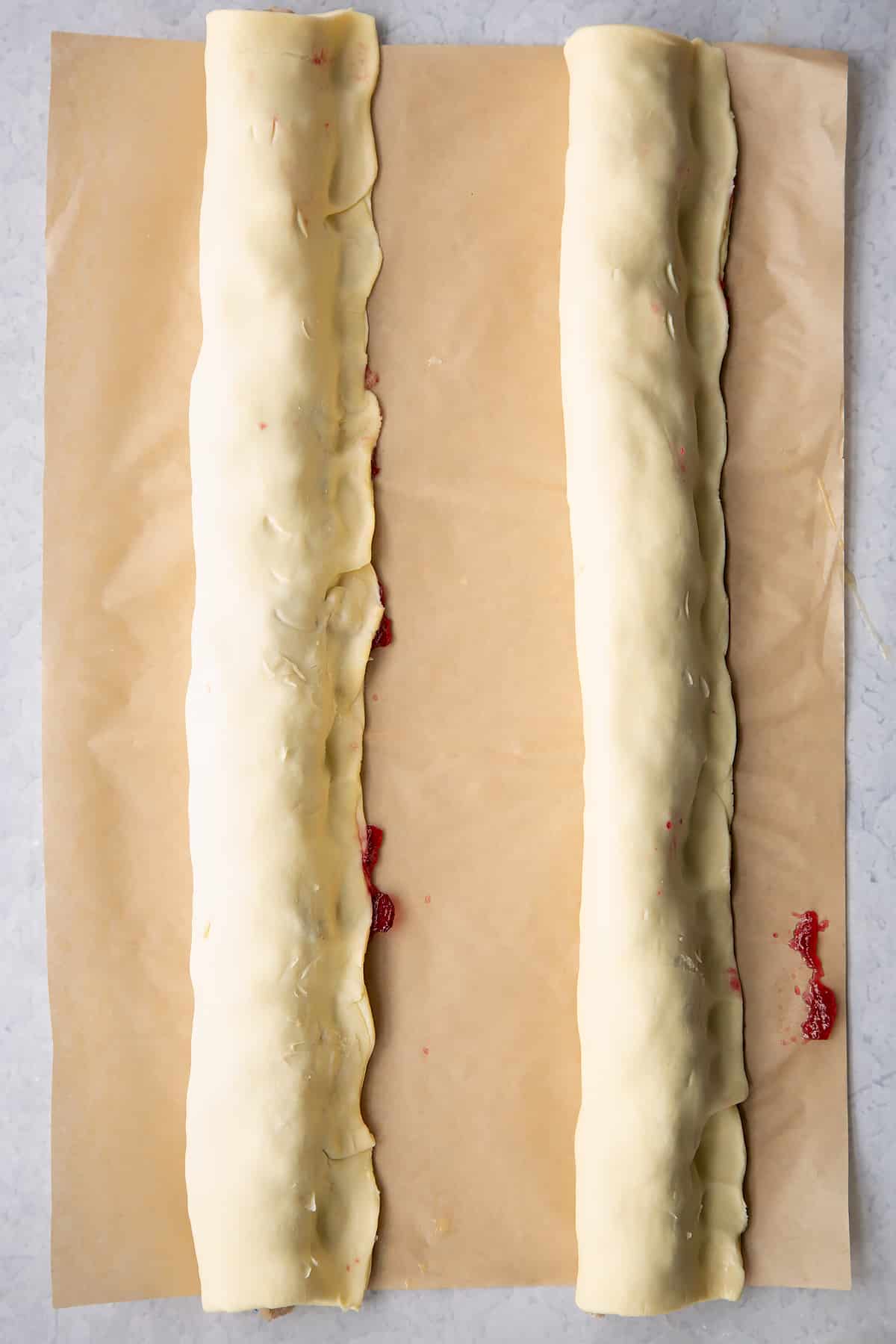 Two lengths of puff pastry wrapped around two lengths of festive sausage meat.