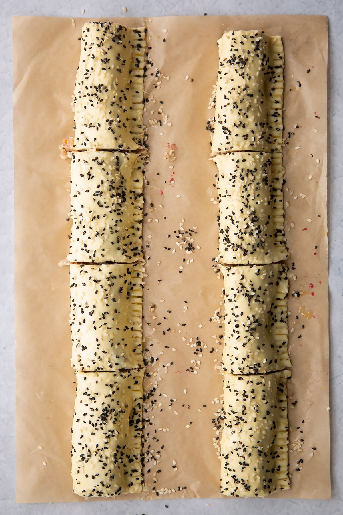 Two lengths of festive sausage meat wrapped in puff pastry , scattered with sesame seeds and cut into 8
in total.