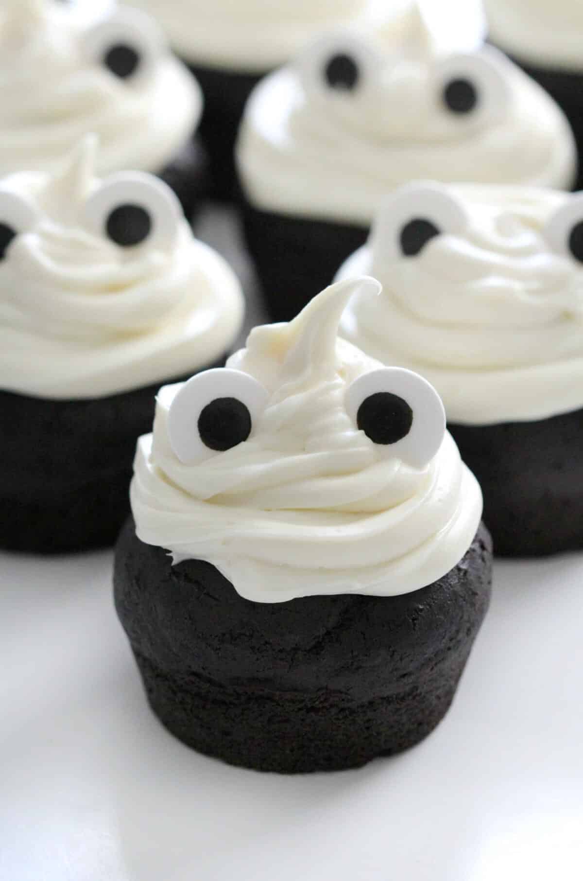 Gluten-free ghost cupcakes: Black cupcakes decorated with white frosting and candy eyes.