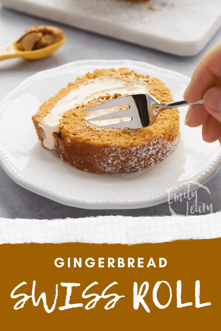 A slice of gingerbread Swiss roll on a white plate with a fork delving in. Caption reads: Gingerbread Swiss roll. 