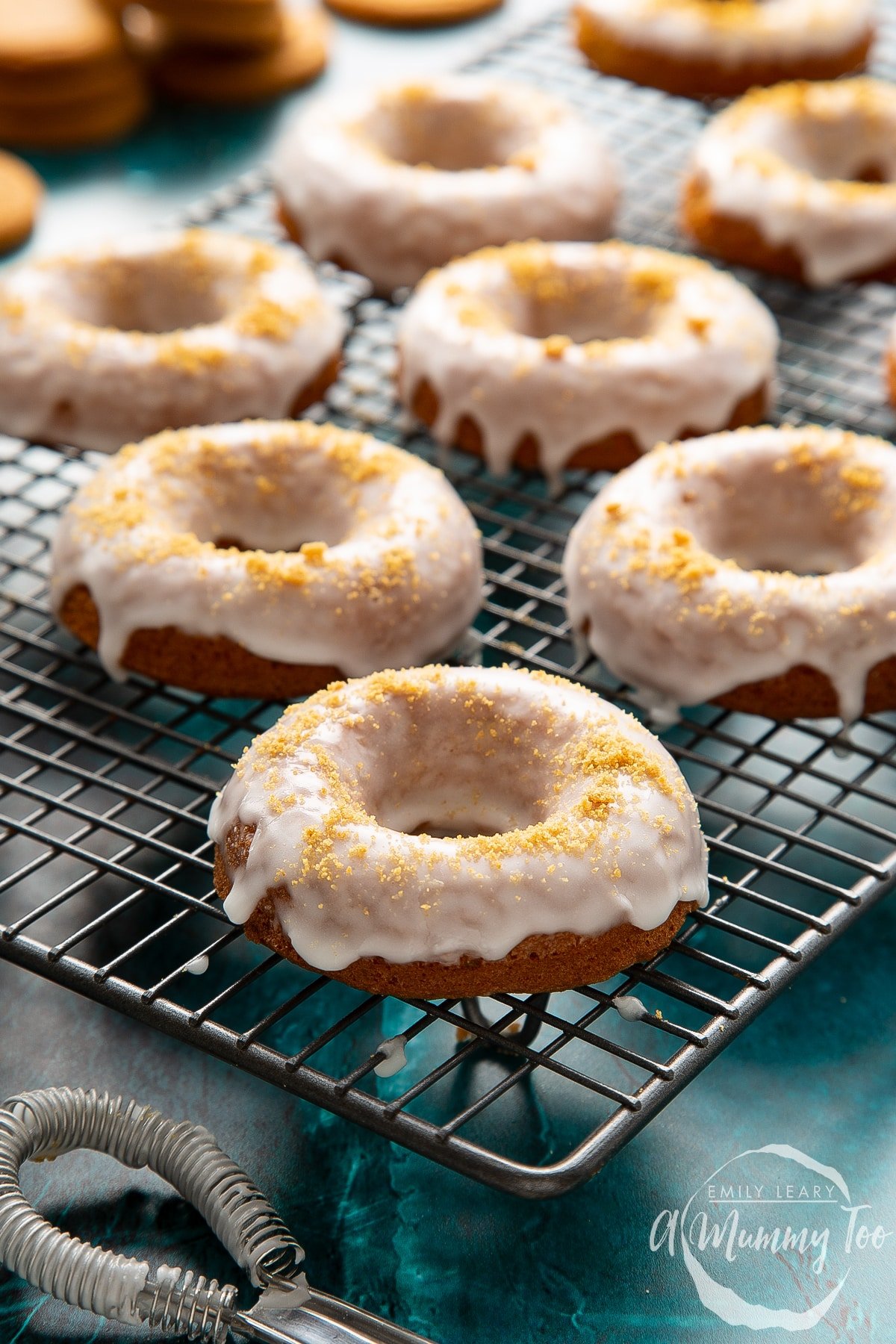 Baked gingerbread donuts with a lemon glaze on a wire cooling rack.