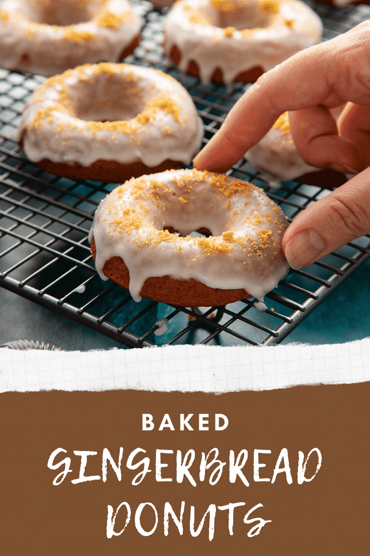 Baked gingerbread donuts with a lemon glaze on a wire cooling rack. A hand reaches for one. Caption reads: Baked gingerbread donuts.