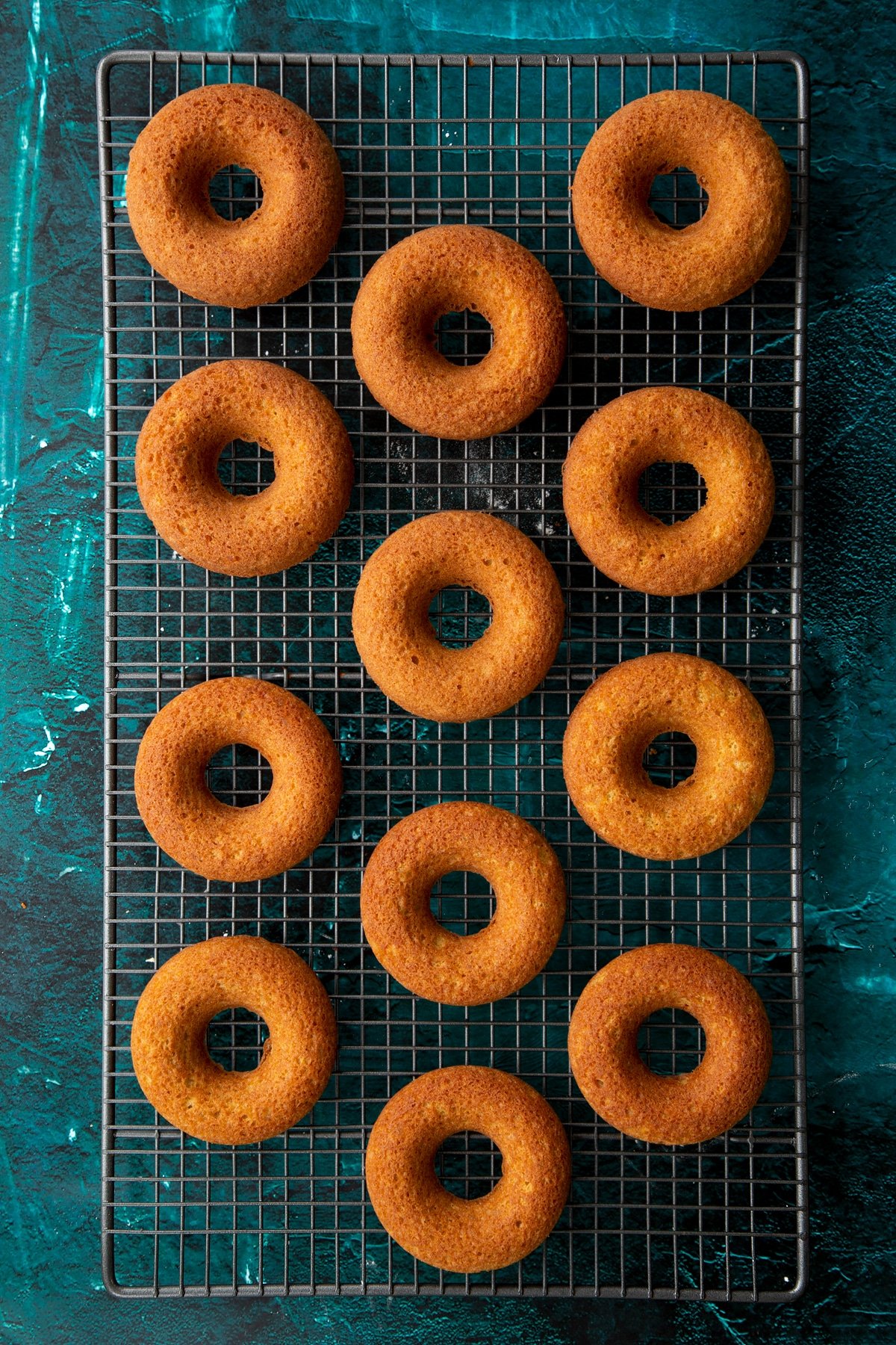 Freshly baked gingerbread donuts on a wire cooling rack.