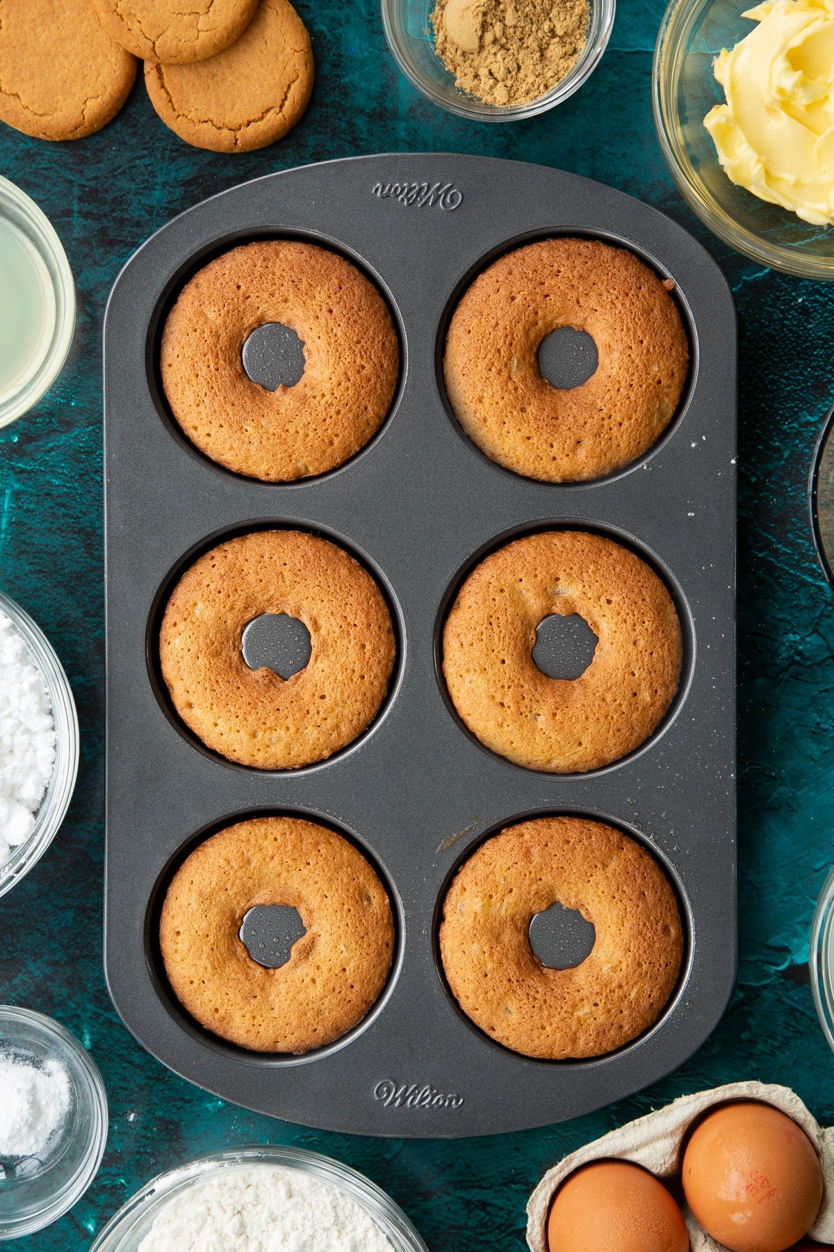 Freshly baked gingerbread donuts in a metal donut pan.