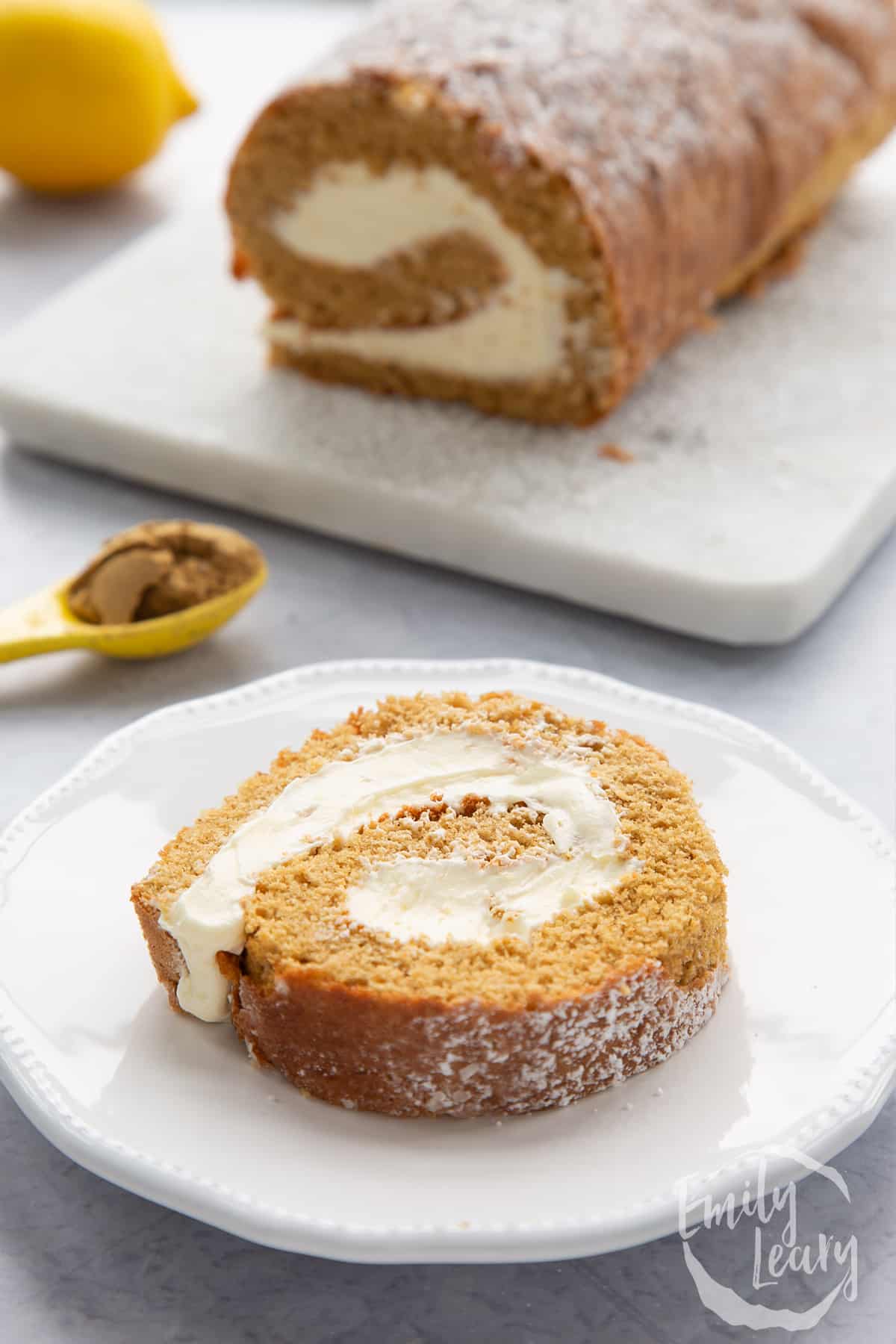 A slice of gingerbread Swiss roll on a white plate.