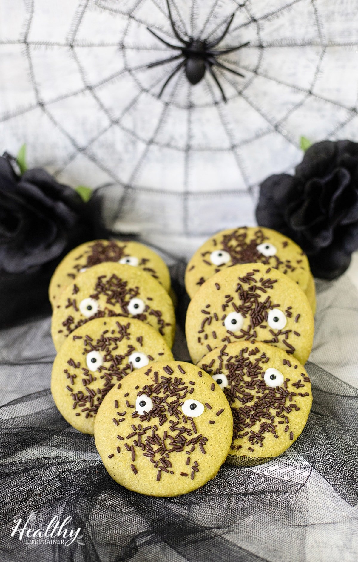 Matcha spooky Halloween cookies with chocolate sprinkles and candy eyes.