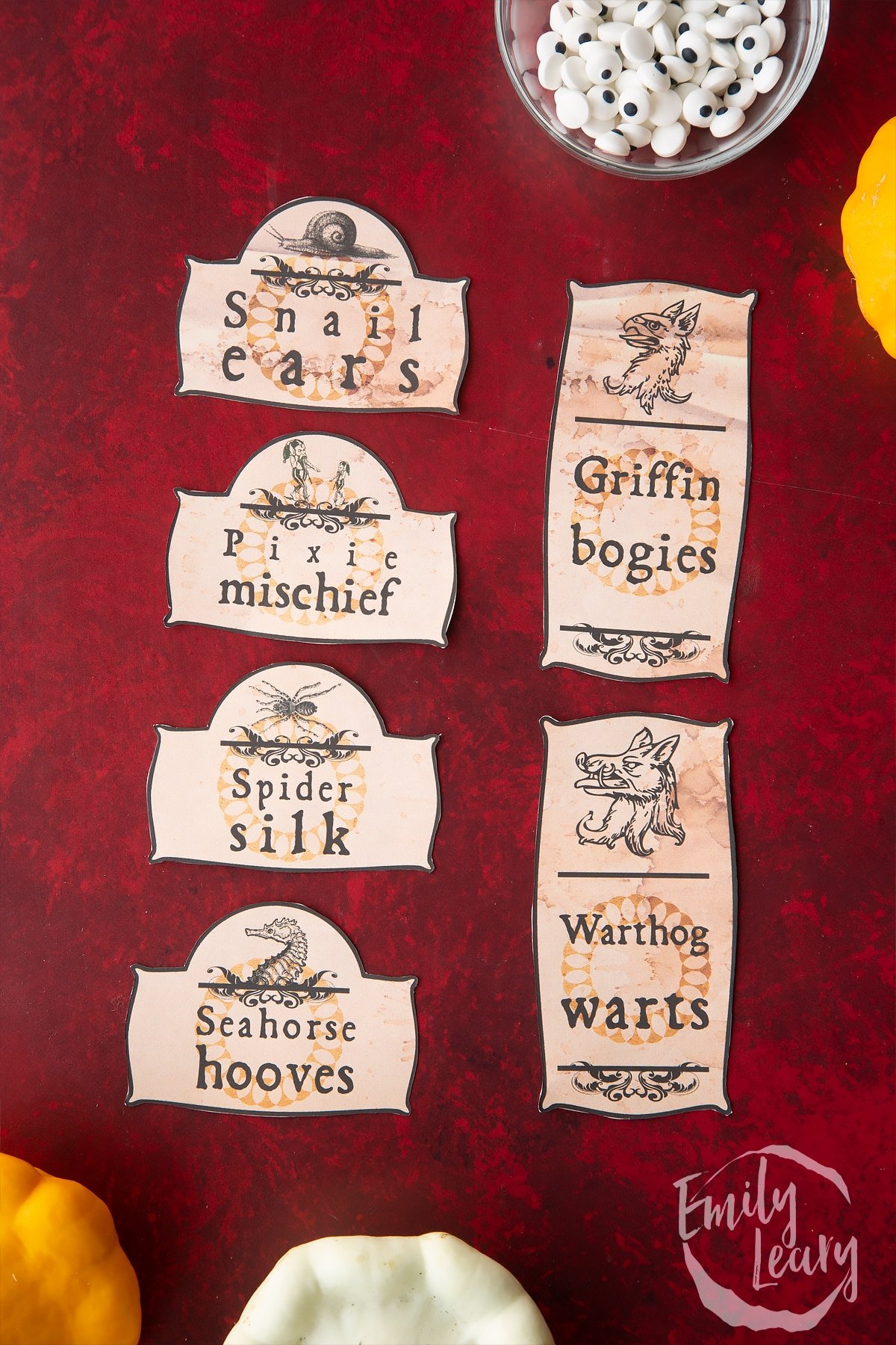 Cut out Halloween apothecary labels arranged on a red background.