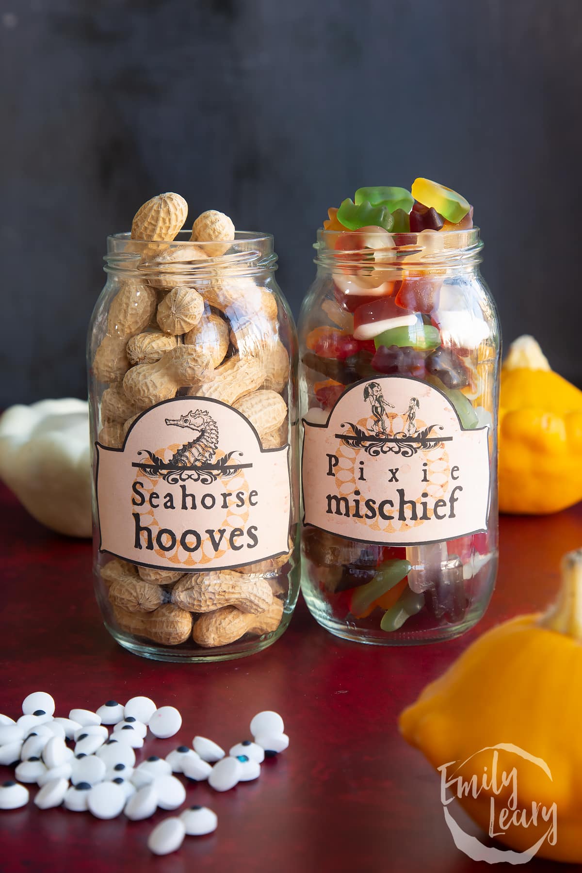 Two jars of different sizes, bearing Halloween apothecary labels. The jars contain Monkey Nuts (Seahorse hooves) and mini gummy sweets (Pixie mischief)