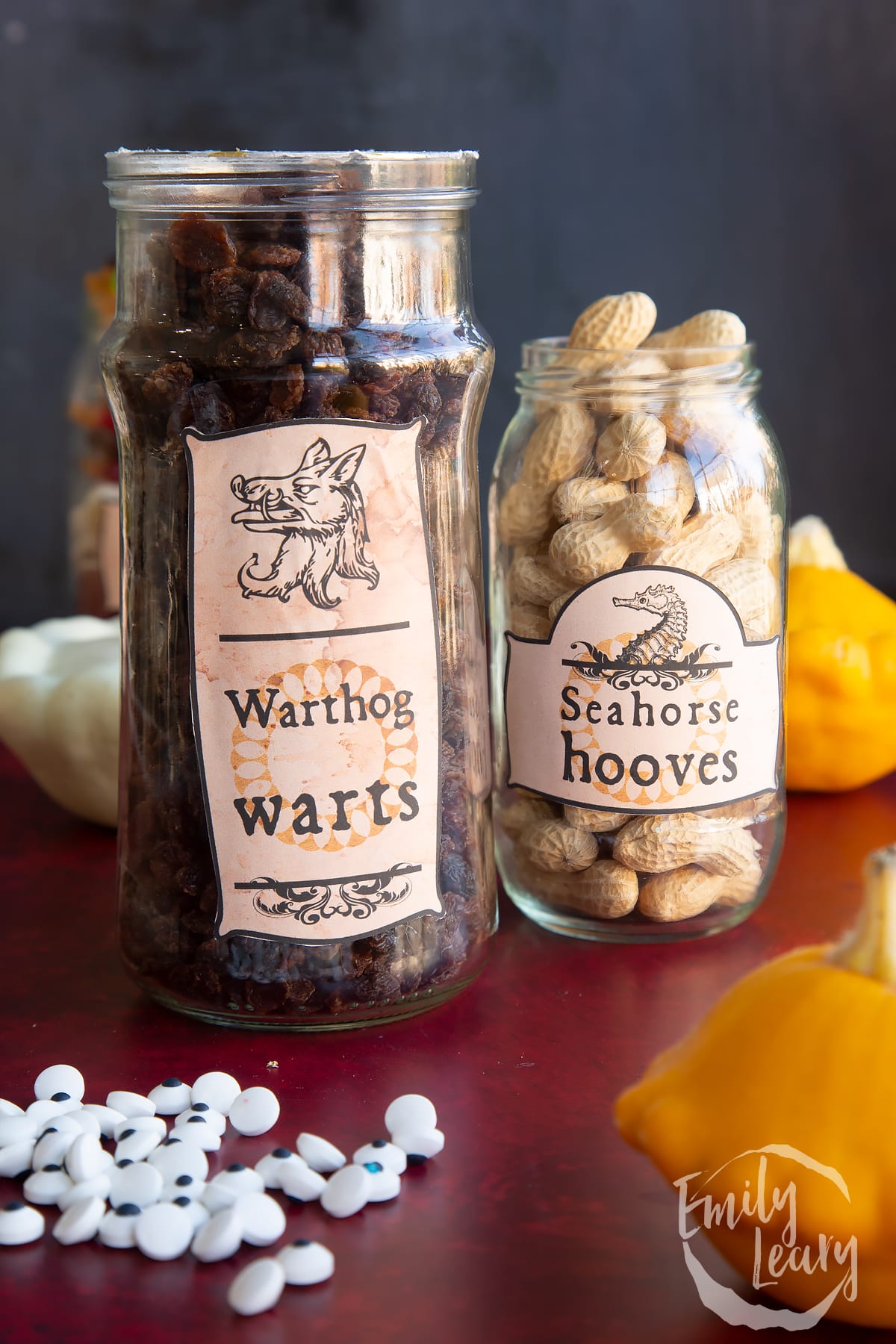 Two jars of different sizes, bearing Halloween apothecary labels. The jars contain raisins (Warthog warts) and Monkey Nuts (Seahorse hooves).