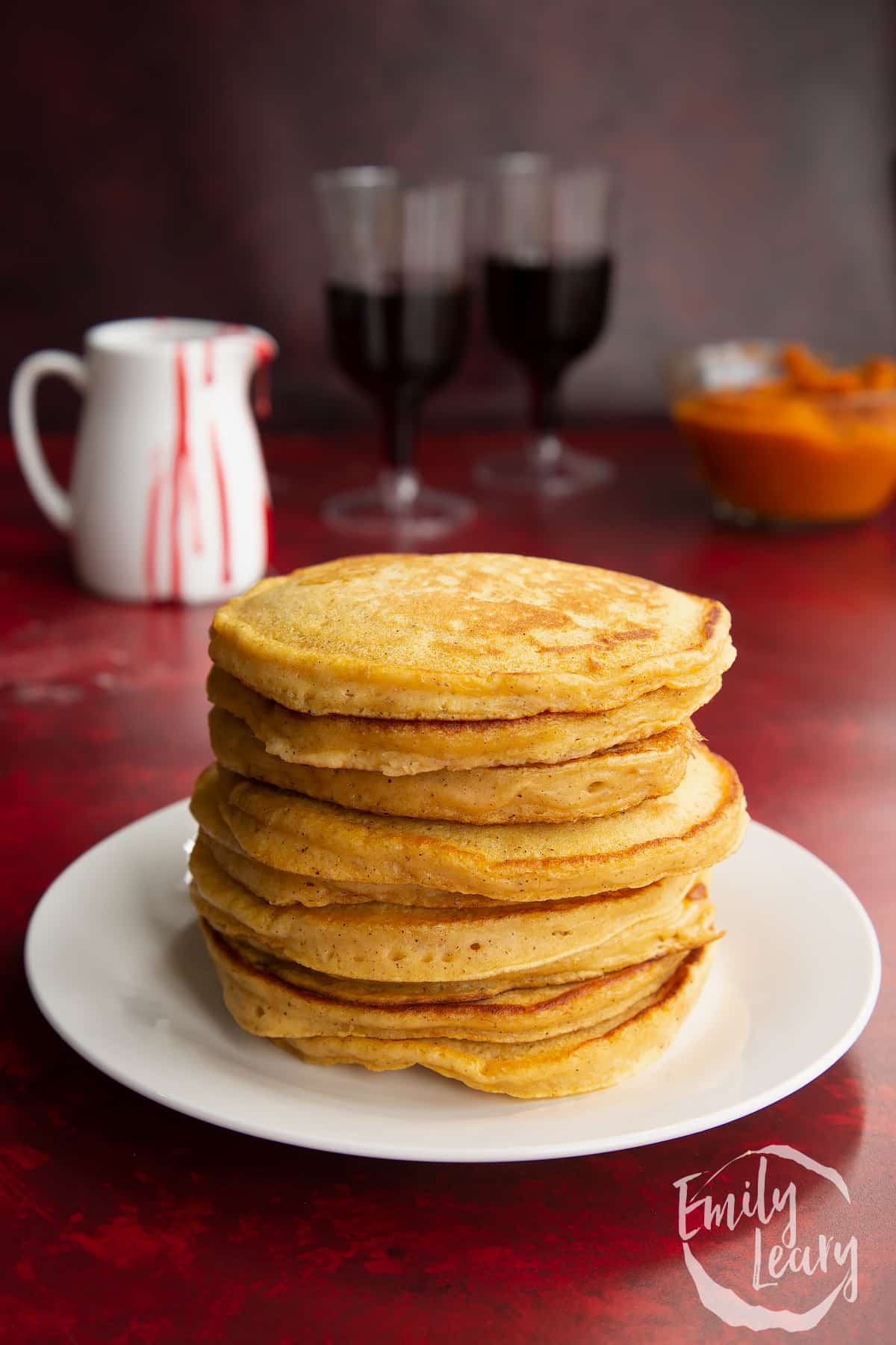 Halloween pumpkin pancakes stacked on a white plate.