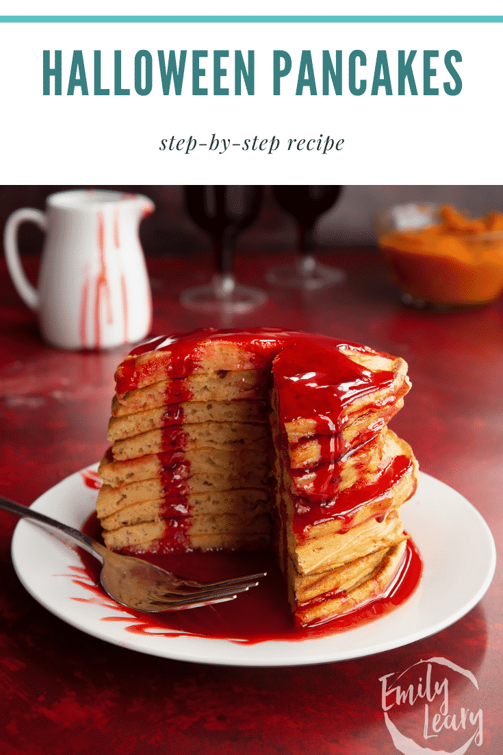 Halloween pancakes stacked on a white plate, drizzled with red syrup. A section has been cut away. Caption reads: Halloween pancakes. Step-by-step recipes. 