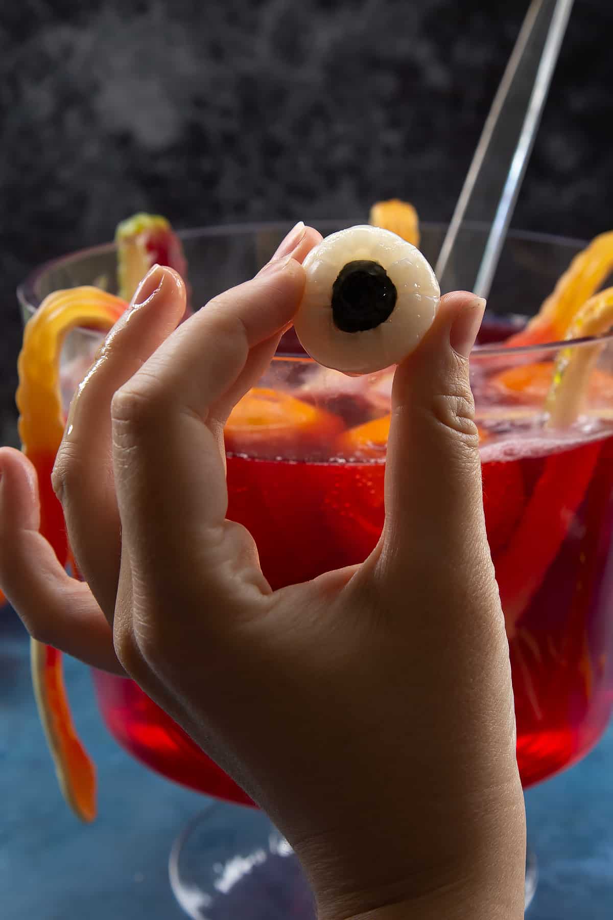 Hand holding a lychee with a blueberry pressed into the centre to resemble an eye.