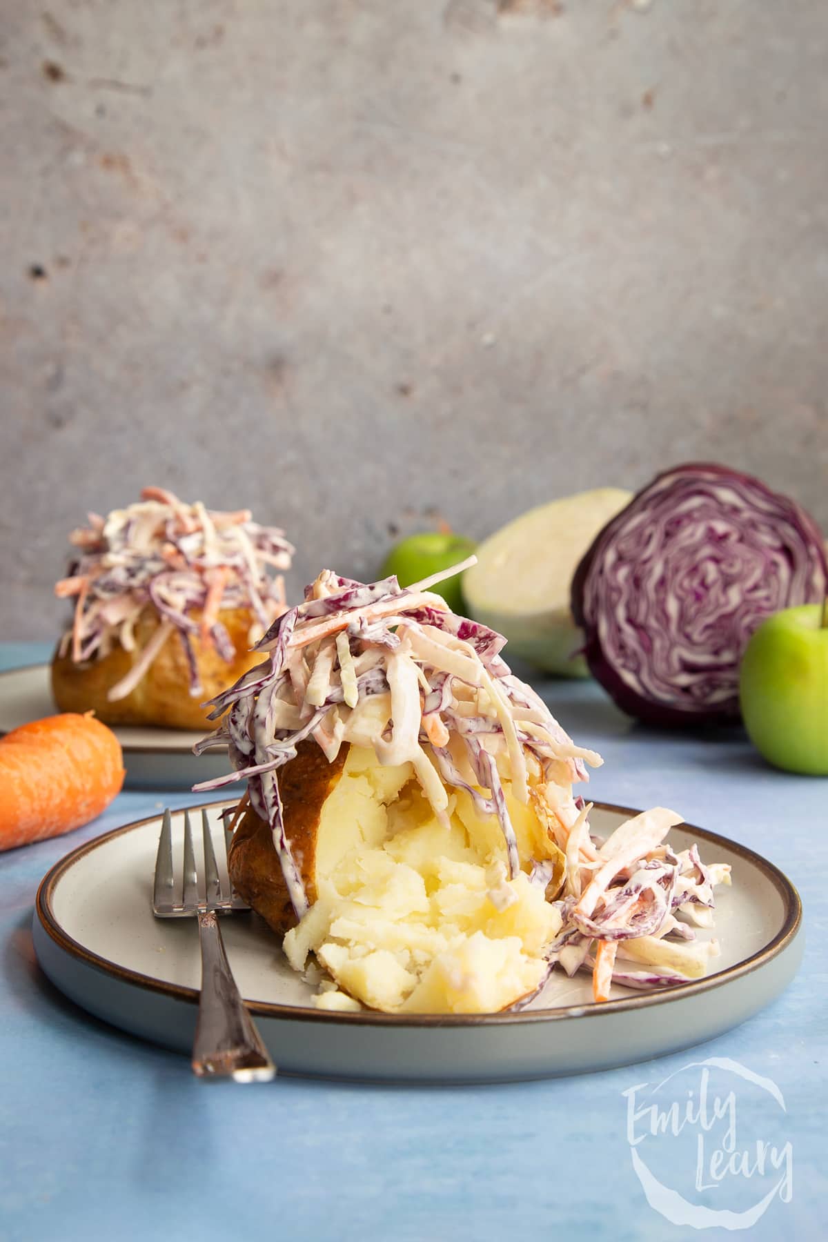 Jacket potato with cut open with homemade coleslaw on a plate with a fork.