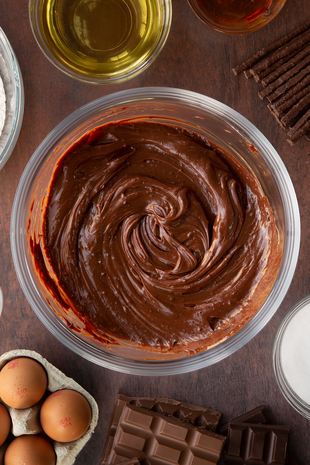 Matchmaker ganache in a glass mixing bowl. Ingredients to make Matchmaker cake surround the bowl. 