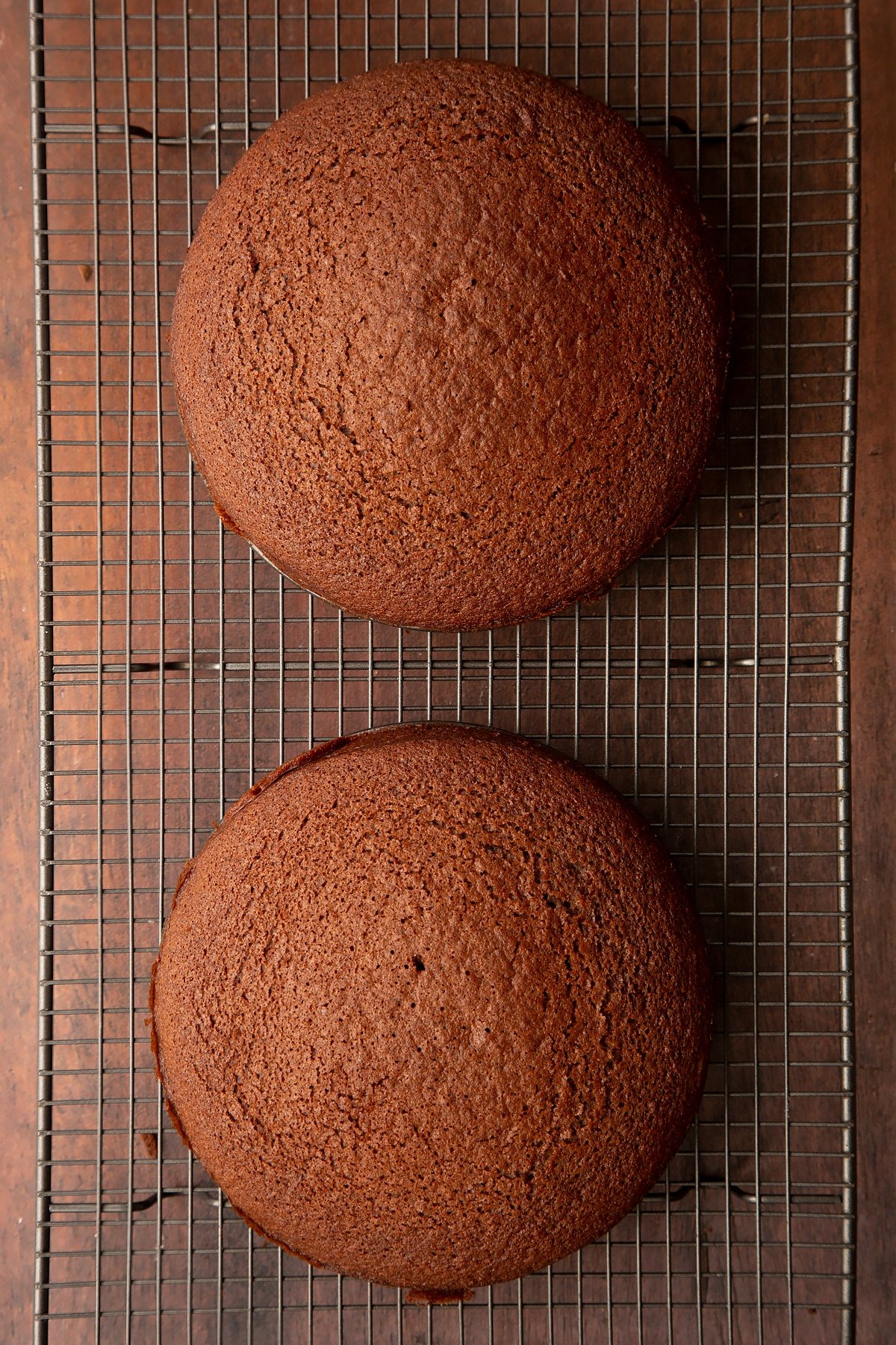 Two chocolate cakes on a wire rack.