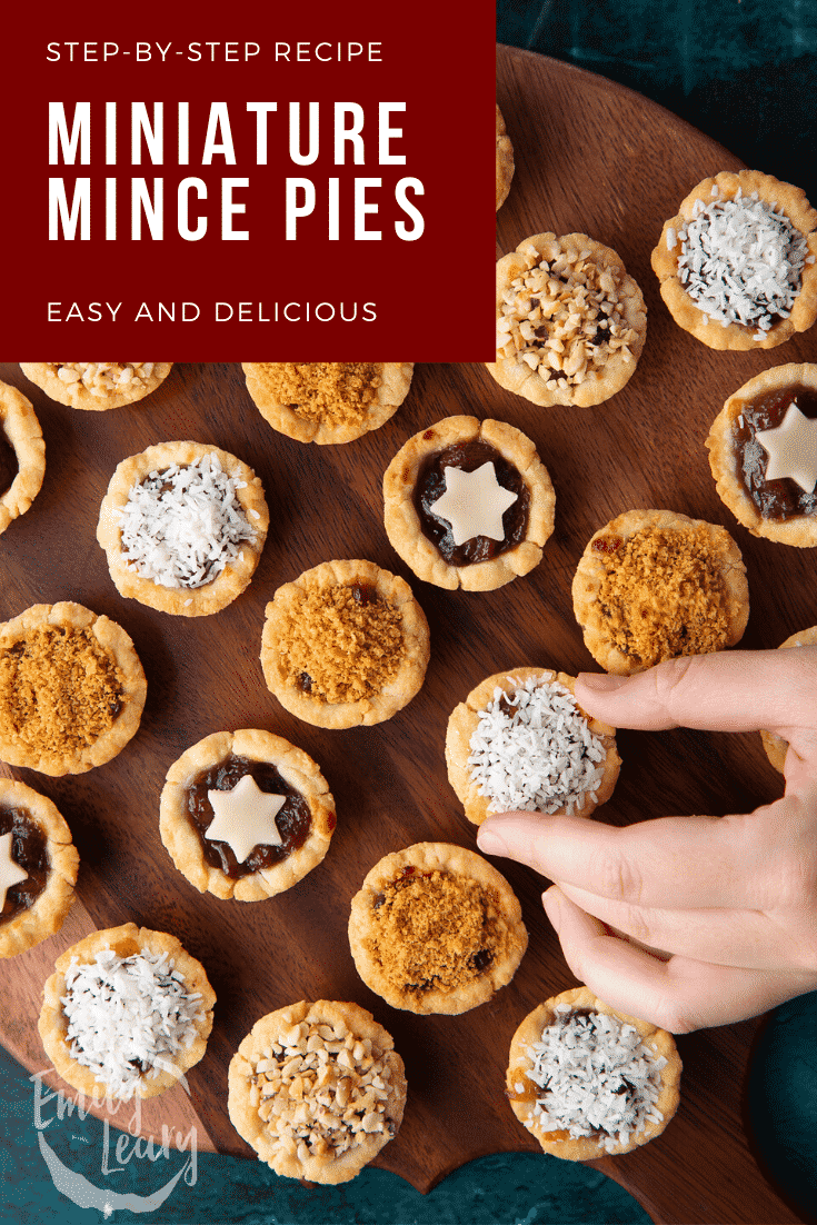 Mini mince pies on a dark wooden board, shown from above. A hand takes one. Caption reads: Step-by-step recipe. Miniature mince pies. Easy and delicious.