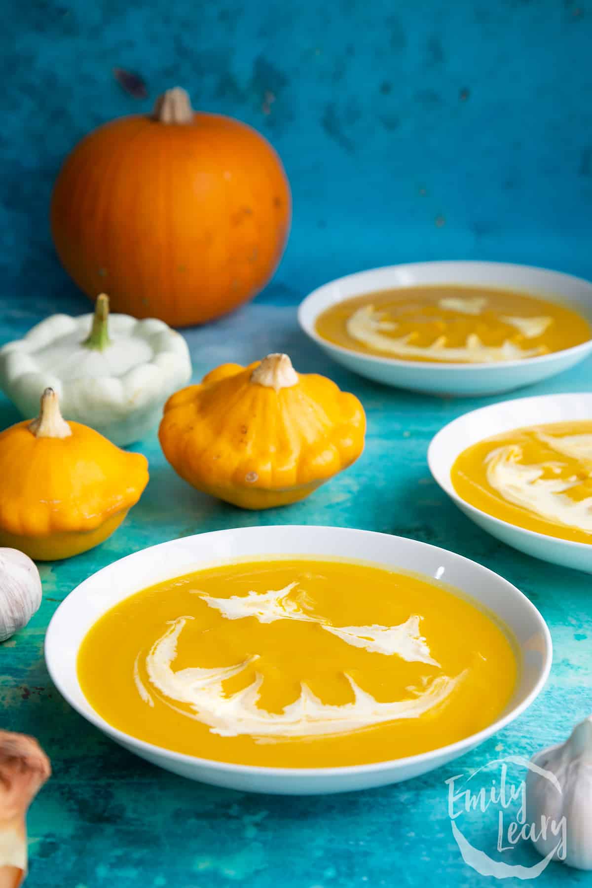 Pumpkin and sweet potato soup in a white bowl. The soup has cream swirled on top to resemble a jack'o'lantern.