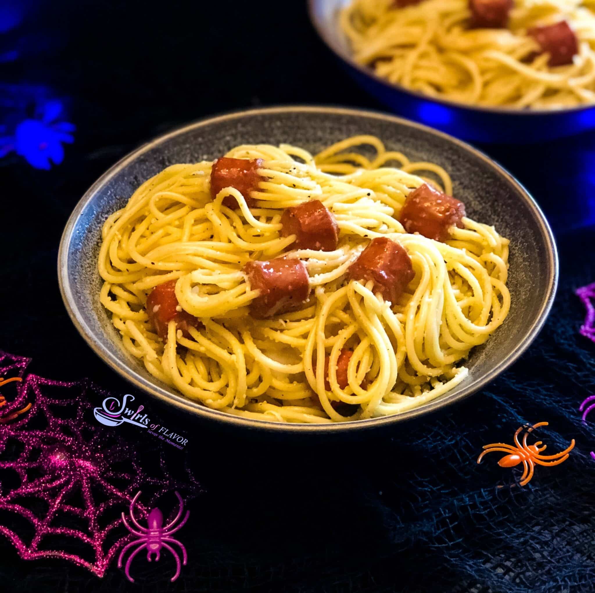 Hot dog spaghetti served in a bowl on a dark background.