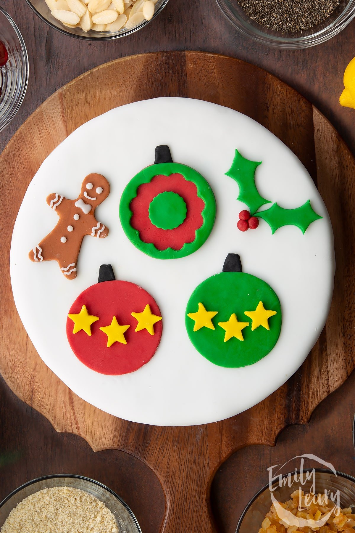 Vegan Christmas cake, topped with a disc of marzipan, covered with white sugar paste and decorated with sugar paste decorations (three baubles, a sprig of holly and a little gingerbread man).