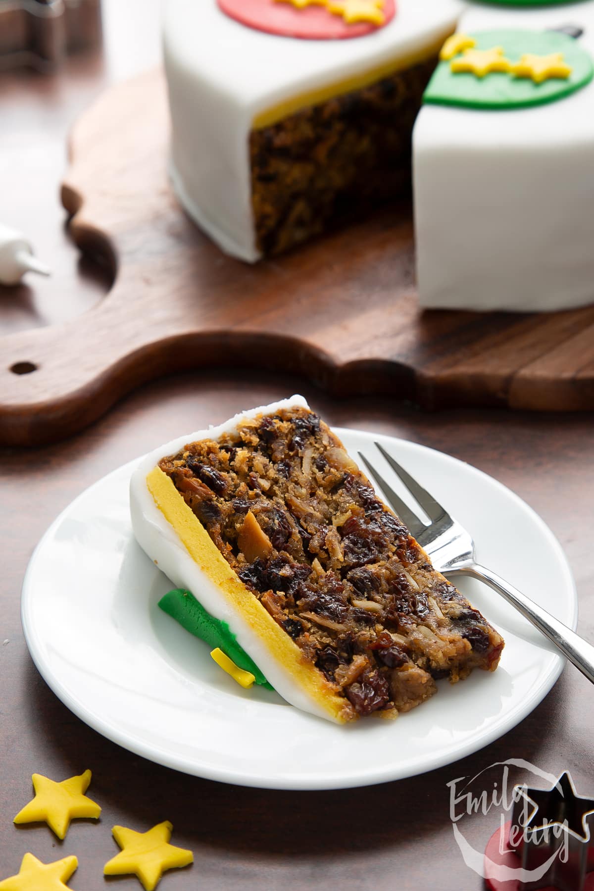 Slice of vegan Christmas cake on a white plate with a fork. 