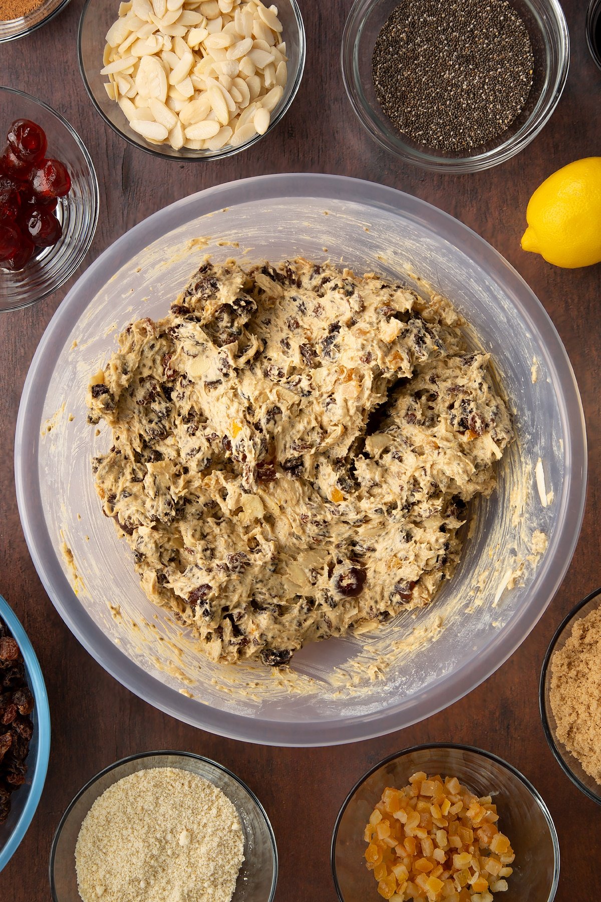 Vegan Christmas cake batter in a bowl. Ingredients to make vegan Christmas cake surround the bowl.