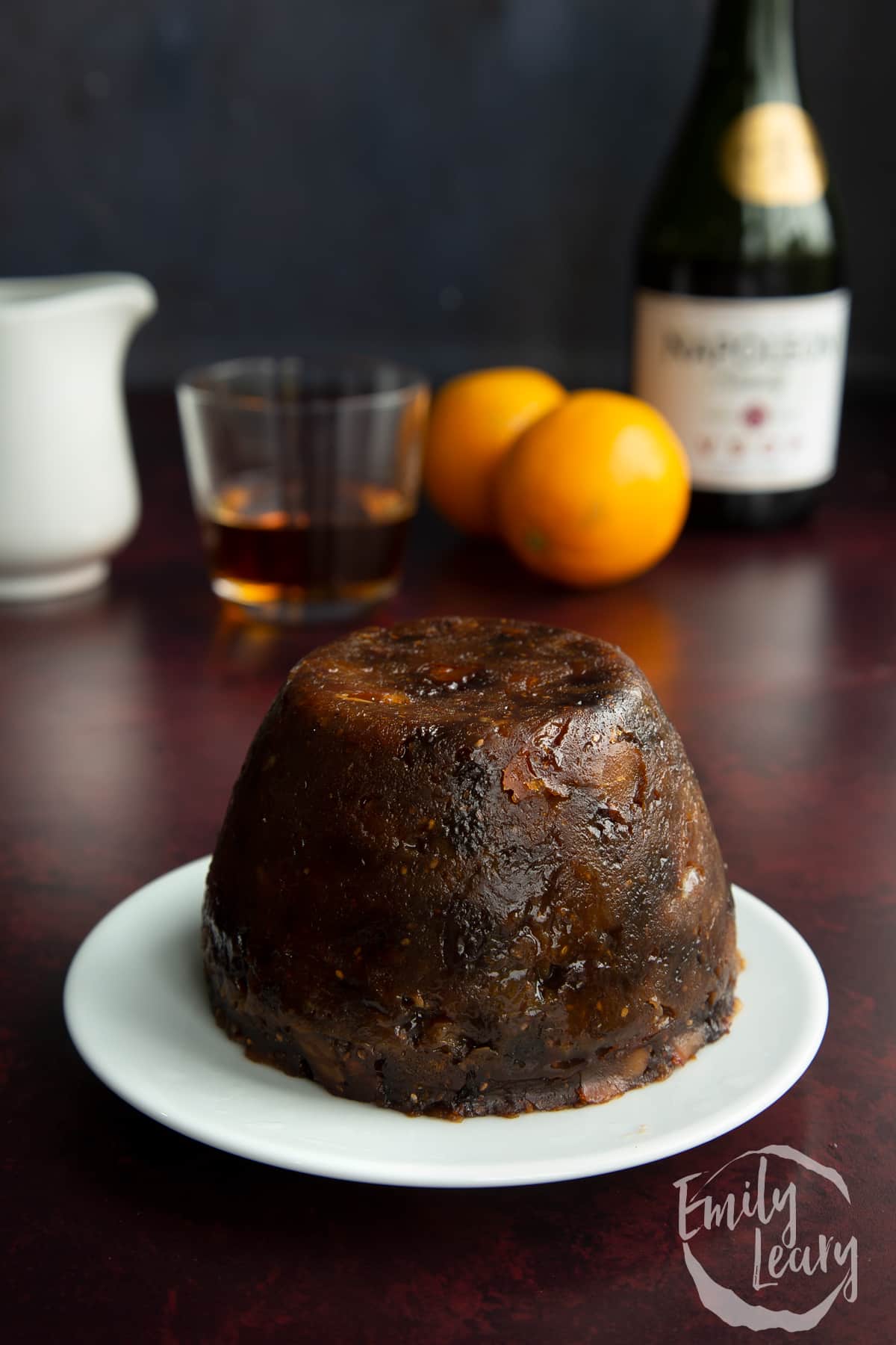 Steamed vegan Christmas pudding on a small white plate.