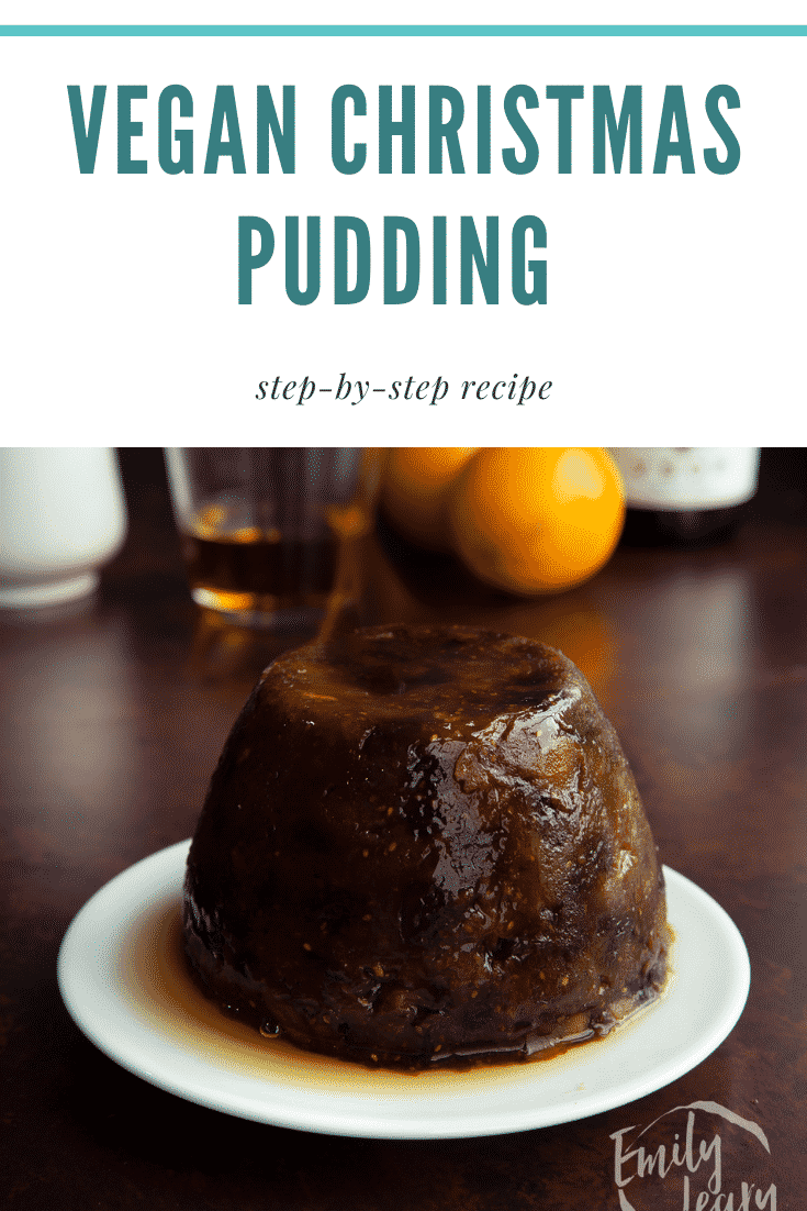 Vegan Christmas pudding on a white plate with whisky. Caption reads: Vegan Christmas pudding step-by-step recipe