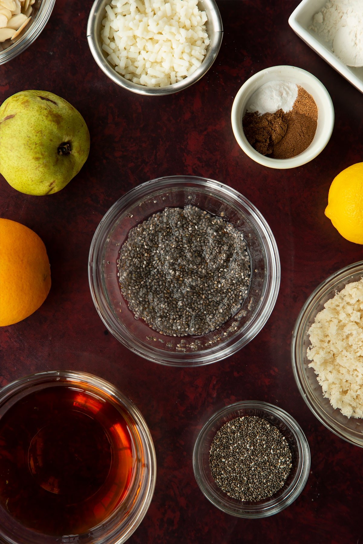 Soaked chia seeds in a small glass bowl. Ingredients to make vegan Christmas pudding surround the bowl. 