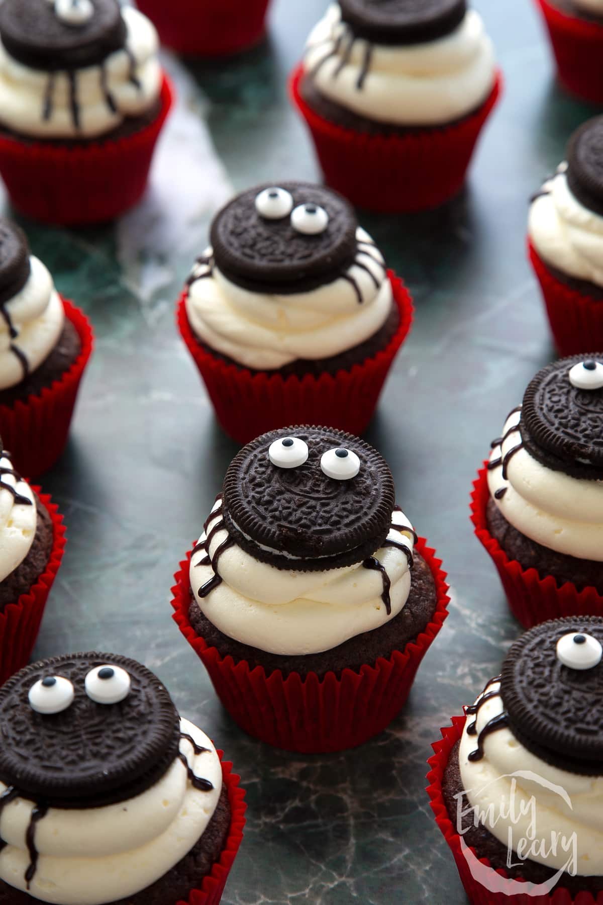 Vegan Halloween cupcakes, decorated with Oreos and candy eyes to look like spiders on top of the frosting.