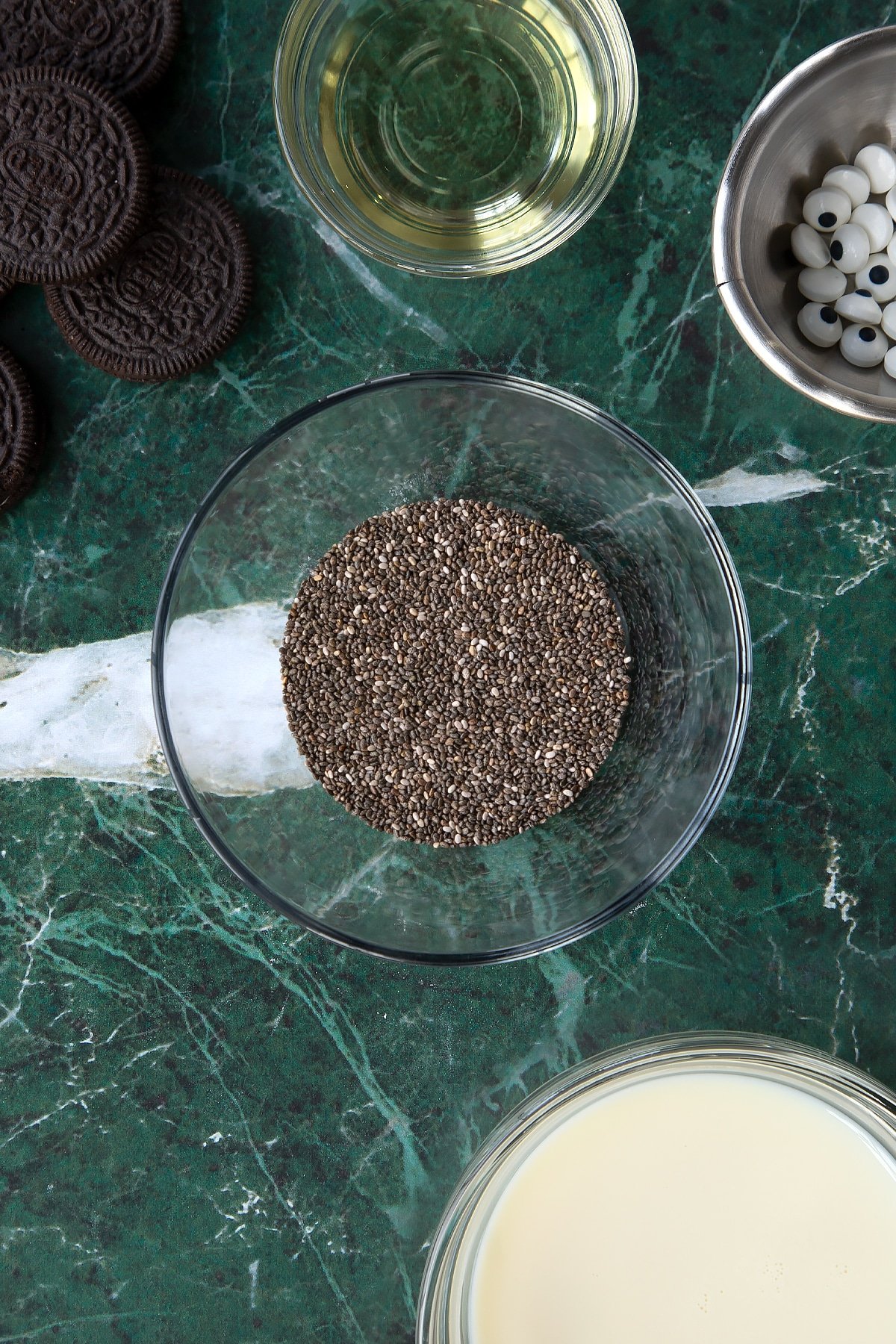 Chia seeds in a small glass bowl. Ingredients to make vegan Halloween cupcakes surround the bowl.