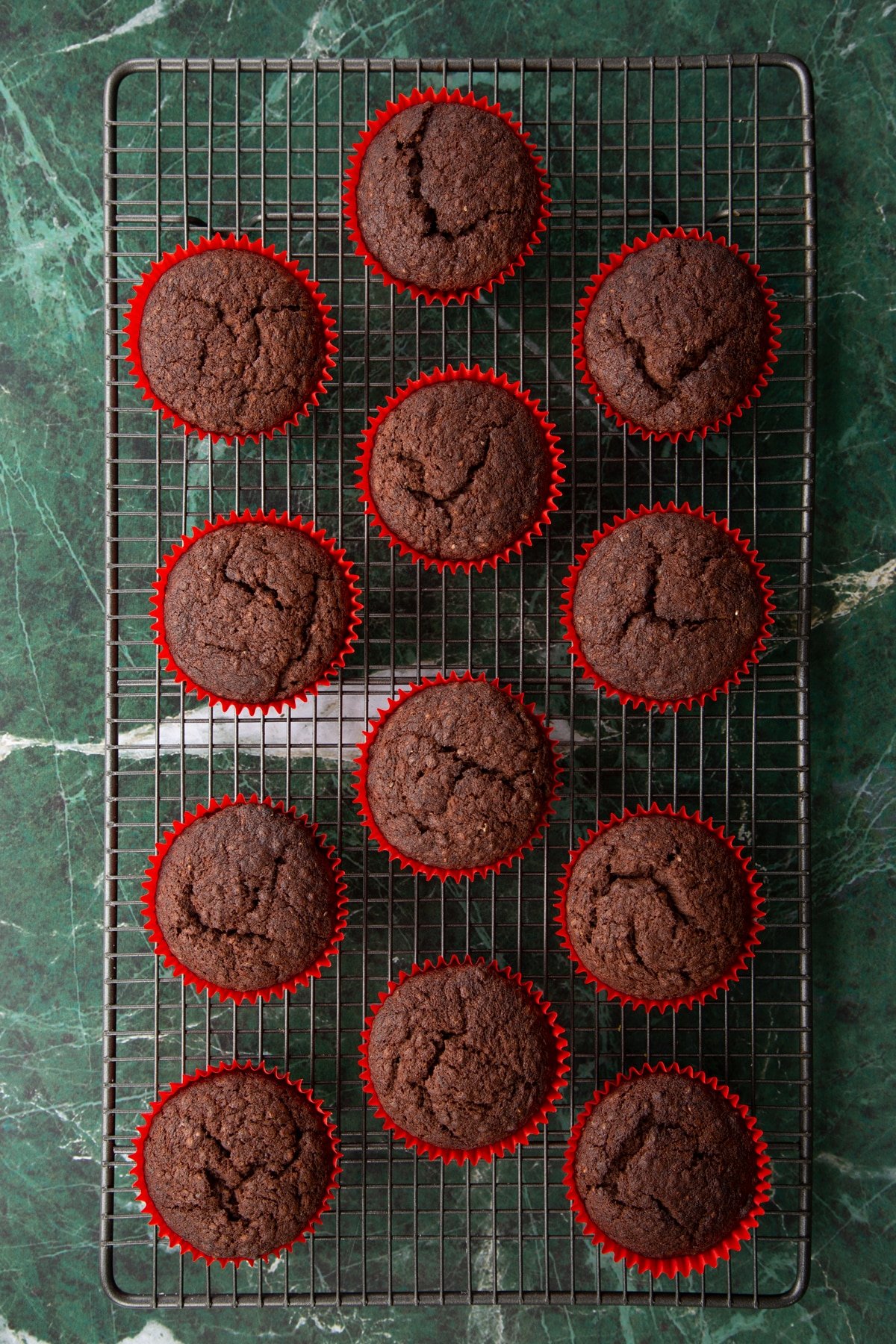 Freshly baked vegan chocolate cupcakes on a wire cooling rack.