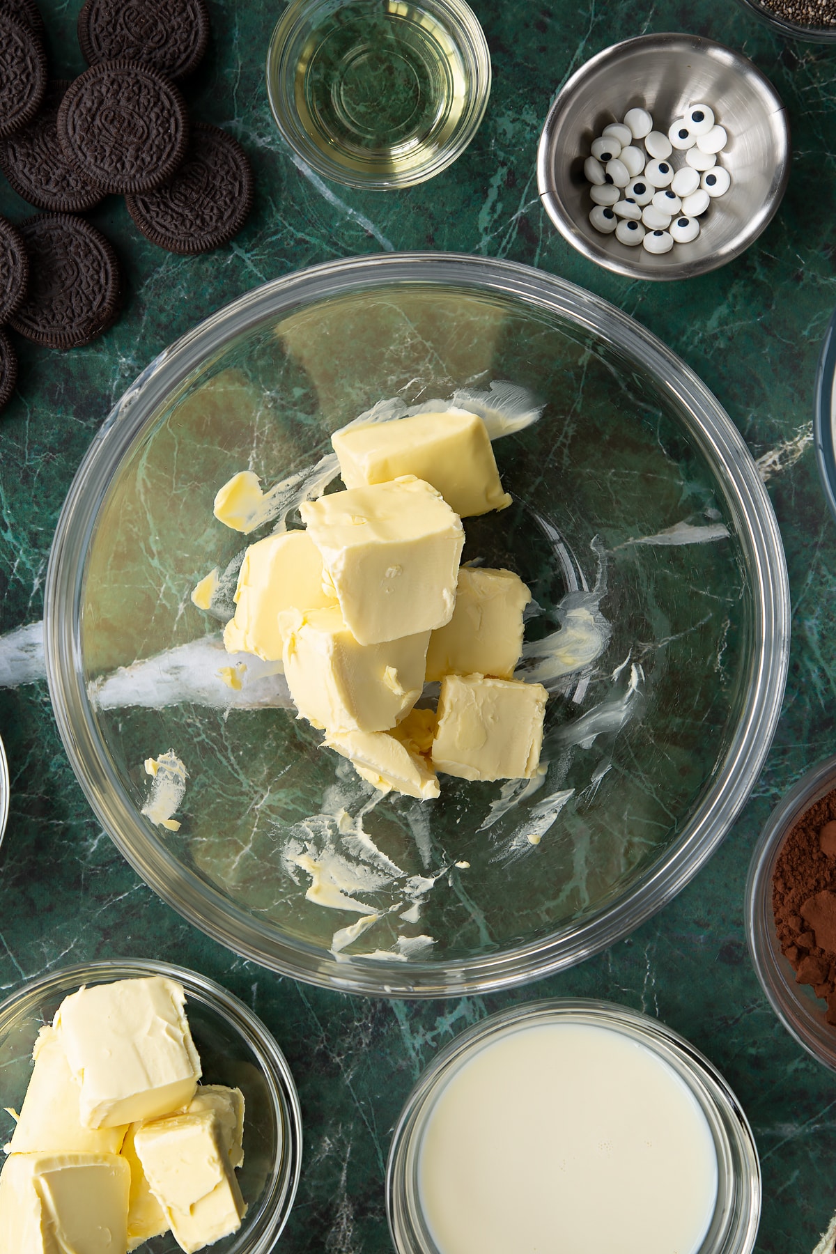 Vegan butter in a glass mixing bowl. Ingredients to make vegan Halloween cupcakes surround the bowl.