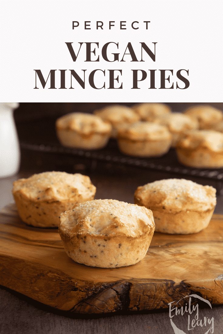 Vegan mince pies on a olive board with more on a wire rack in the background. Captions reads: Perfect vegan mince pies