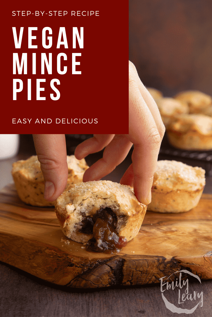 Vegan mince pies on a olive board with more on a wire rack in the background. One has been bitten open and a hand reaches for it. Captions reads: Step-by-step recipe vegan mince pies. Easy and delicious