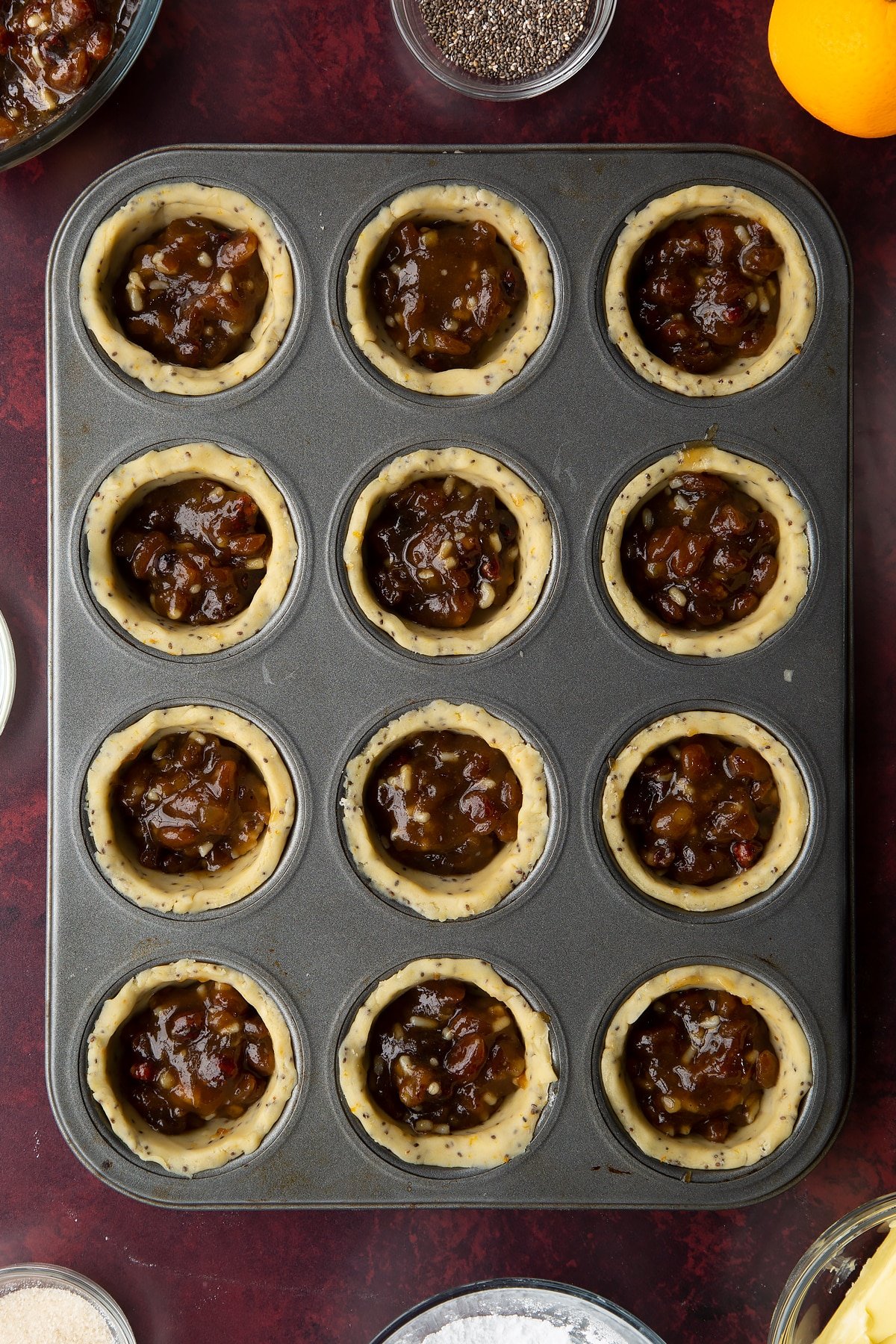 12-hole muffin tray lined with vegan pastry and filled with mincemeat.