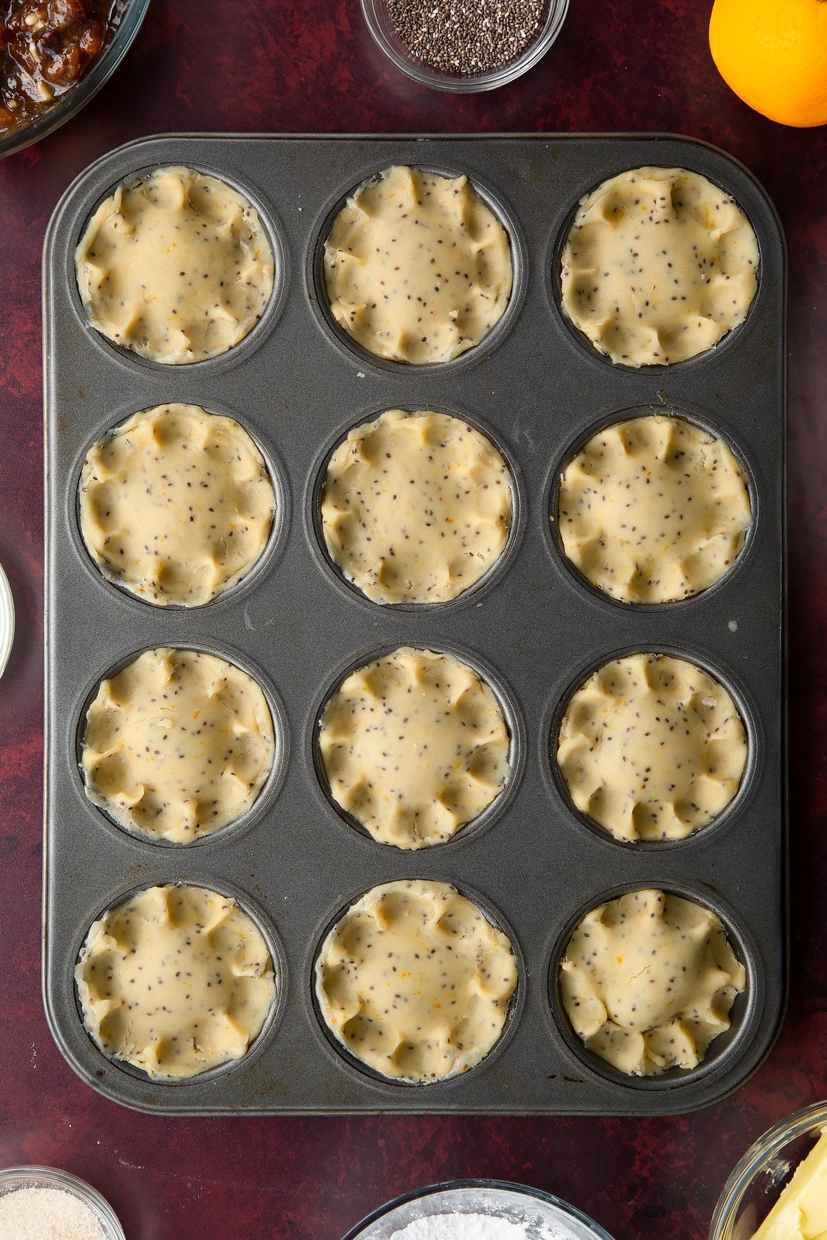 Uncooked vegan mince pies in a 12-hole muffin tray.