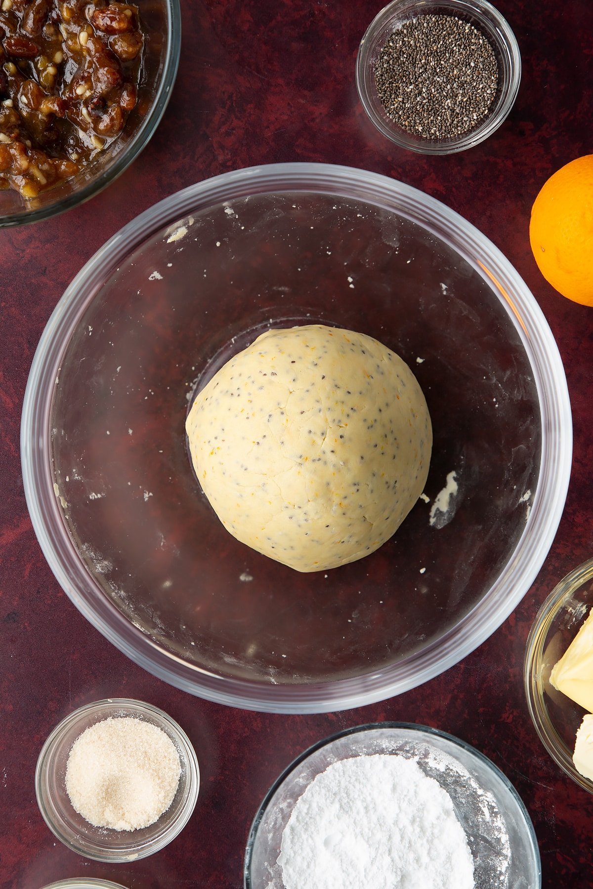 A ball of vegan pastry in a bowl. Ingredients to make a vegan mince pie recipe surround the bowl.