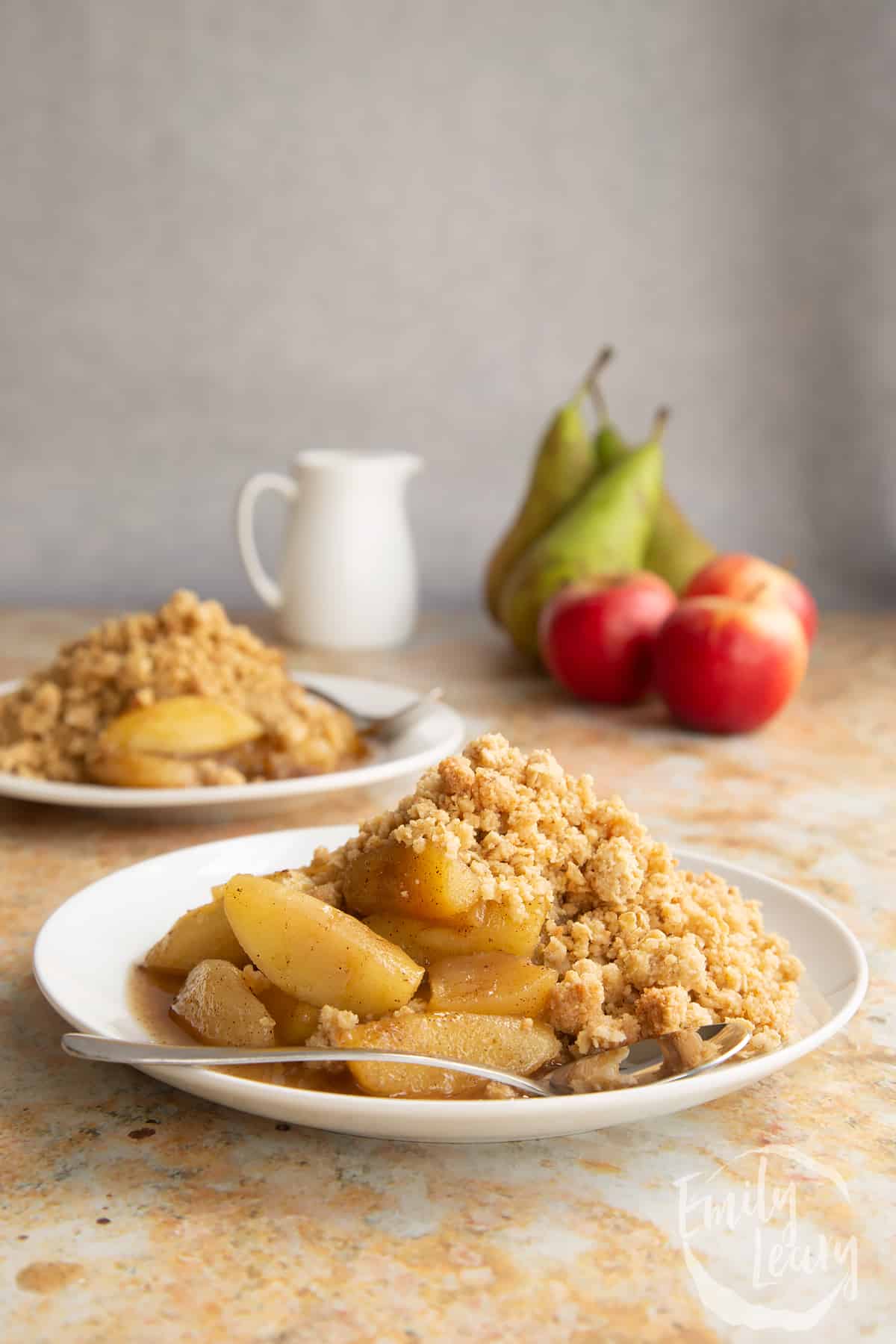 Apple pear crumble served to a small white plate with a small spoon.