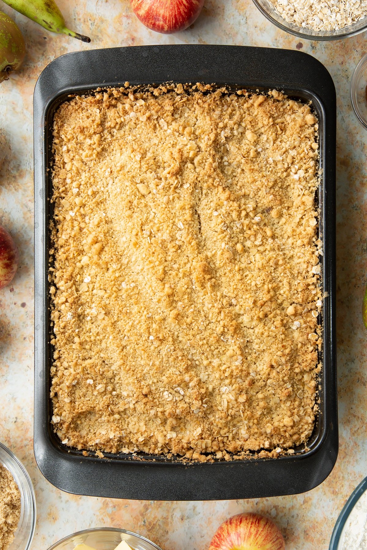 Freshly baked apple and pear crumble in a metal tray.